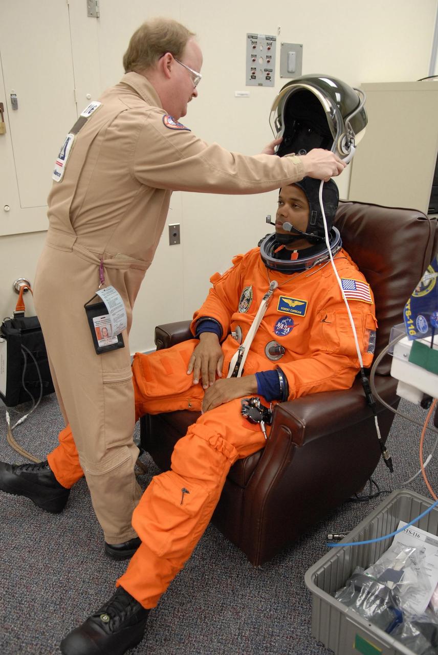 KENNEDY SPACE CENTER, FLA. -- The crew members of mission STS-116 are suiting up for launch at 9:35 p.m. EST from Launch Pad 39B aboard Space Shuttle Discovery. Pictured here is Mission Specialist Robert Curbeam, waiting for the suit technician to place the helmet. Curbeam will be making his third shuttle flight. This is Discovery's 33rd mission and the first night launch since 2003. The 20th shuttle mission to the International Space Station, STS-116 carries another truss segment, P5. It will serve as a spacer, mated to the P4 truss that was attached in September. After installing the P5, the crew will reconfigure and redistribute the power generated by two pairs of U.S. solar arrays. Landing is expected Dec. 19 at KSC. Photo credit: NASA/Kim Shiflett