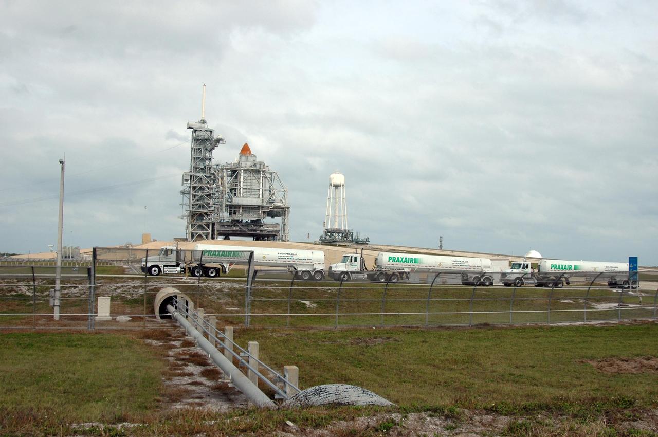 KENNEDY SPACE CENTER, FLA. -- Fuel trucks head for Launch Pad 39B to refill the external tank on Space Shuttle Discovery. The top of the external tank can be seen above the rotating service structure that encloses the space shuttle. The launch attempt of Discovery on mission STS-116 was postponed Dec. 7 due a low cloud ceiling over Kennedy Space Center. The next launch attempt was scheduled for Saturday, Dec. 9, at 8:47 p.m. This will be Discovery's 33rd mission and the first night launch since 2002. The 20th shuttle mission to the International Space Station, STS-116 carries another truss segment, P5. It will serve as a spacer, mated to the P4 truss that was attached in September. After installing the P5, the crew will reconfigure and redistribute the power generated by two pairs of U.S. solar arrays. Landing is expected Dec. 19 at KSC. Photo credit: NASA/Ken Thornsley