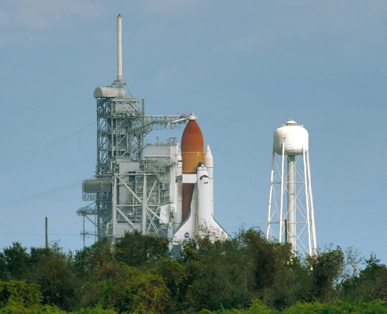 KENNEDY SPACE CENTER, FLA. --   On the morning of the second launch attempt, Space Shuttle Discovery is revealed after rollback of the rotating service structure.  Seen above the golden external tank is the vent hood (known as the "beanie cap") at the end of the gaseous oxygen vent arm, extending from the fixed service structure. Vapors are created as the liquid oxygen in the external tank boil off. The hood vents the gaseous oxygen vapors away from the space shuttle vehicle. Below it, also extending toward Discovery from the FSS, is the orbiter access arm with the White Room at the end. The crew gains access into the orbiter through the White Room.  Atop the FSS is the 80-foot-tall lightning mast.  To the right of the shuttle is the water tower, containing 300 gallons of water used for sound suppression at liftoff. The first launch attempt of STS-116 Dec. 7 was postponed due a low cloud ceiling over Kennedy Space Center. The next launch attempt was scheduled for Saturday, Dec. 9, at 8:47 p.m. This will be Discovery's 33rd mission and the first night launch since 2002.   The 20th shuttle mission to the International Space Station, STS-116 carries another truss segment, P5. It will serve as a spacer, mated to the P4 truss that was attached in September.  After installing the P5, the crew will reconfigure and redistribute the power generated by two pairs of U.S. solar arrays. Landing is expected Dec. 19 at KSC.  Photo credit: NASA/Ken Thornsley