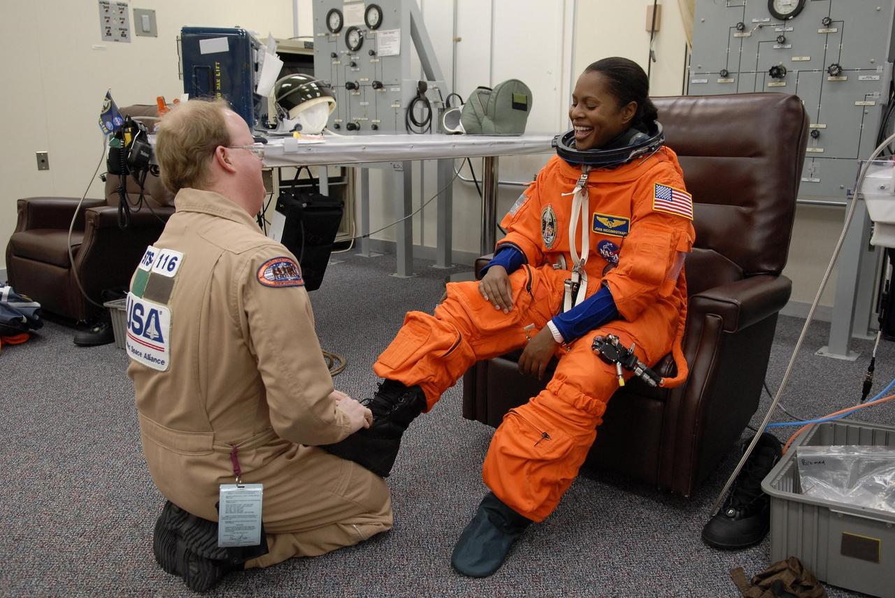 KENNEDY SPACE CENTER, FLA. --   The crew members of mission STS-116 are suiting up for a second launch attempt at 8:47 p.m. EST from Launch Pad 39B aboard Space Shuttle Discovery.  Pictured here, Mission Specialist Joan Higginbotham, who will be making her first shuttle flight, is helped with her boot. The first launch attempt of STS-116 on Dec. 7 was postponed due a low cloud ceiling over Kennedy Space Center. This is Discovery's 33rd mission and the first night launch since 2002.   The 20th shuttle mission to the International Space Station, STS-116 carries another truss segment, P5. It will serve as a spacer, mated to the P4 truss that was attached in September.  After installing the P5, the crew will reconfigure and redistribute the power generated by two pairs of U.S. solar arrays. Landing is expected Dec. 19 at KSC.   Photo credit: NASA/Kim Shiflett