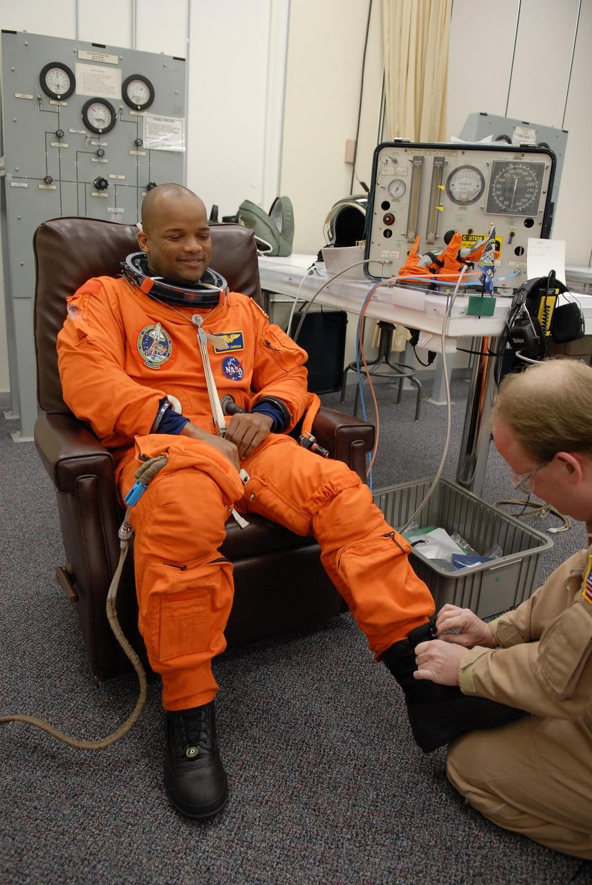 KENNEDY SPACE CENTER, FLA. --   The crew members of mission STS-116 are suiting up for a second launch attempt at 8:47 p.m. EST from Launch Pad 39B aboard Space Shuttle Discovery.  Pictured here is Mission Specialist Robert Curbeam, who is helped with his boot.  Curbeam is making his third shuttle flight.  The first launch attempt of STS-116 on Dec. 7 was postponed due a low cloud ceiling over Kennedy Space Center. This is Discovery's 33rd mission and the first night launch since 2002.   The 20th shuttle mission to the International Space Station, STS-116 carries another truss segment, P5. It will serve as a spacer, mated to the P4 truss that was attached in September.  After installing the P5, the crew will reconfigure and redistribute the power generated by two pairs of U.S. solar arrays. Landing is expected Dec. 19 at KSC.   Photo credit: NASA/Kim Shiflett