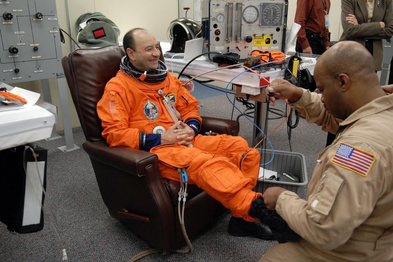 KENNEDY SPACE CENTER, FLA. --   The crew members of mission STS-116 are suiting up for a second launch attempt at 8:47 p.m. EST from Launch Pad 39B aboard Space Shuttle Discovery.  Pictured here is Commander Mark Polansky, being helped with his boot.  Polansky will be making his second shuttle flight. The first launch attempt of STS-116 on Dec. 7 was postponed due a low cloud ceiling over Kennedy Space Center. This is Discovery's 33rd mission and the first night launch since 2002.   The 20th shuttle mission to the International Space Station, STS-116 carries another truss segment, P5. It will serve as a spacer, mated to the P4 truss that was attached in September.  After installing the P5, the crew will reconfigure and redistribute the power generated by two pairs of U.S. solar arrays. Landing is expected Dec. 19 at KSC.   Photo credit: NASA/Kim Shiflett