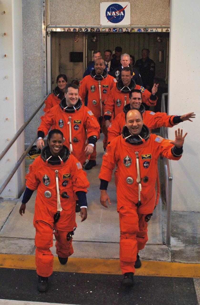 KENNEDY SPACE CENTER, FLA. --    The STS-116 crew members show their eagerness for the second launch attempt as they exit the Operations and Checkout Building.  Commander Mark Polansky (front at right) leads the way.  Behind him are Pilot William Oefelein and Mission Specialist Christer Fuglesang, who represents the European Space Agency.  On the left side, front to back are Mission Specialists Joan Higginbotham,  Nicholas Patrick, Sunita Williams, and Robert Curbeam.  Williams will replace Expedition 14 crew member Thomas Reiter, who will return to Earth aboard Discovery in her place. The first launch attempt of STS-116 on Dec. 7 was postponed due a low cloud ceiling over Kennedy Space Center. This is Discovery's 33rd mission and the first night launch since 2002.   The 20th shuttle mission to the International Space Station, STS-116 carries another truss segment, P5. It will serve as a spacer, mated to the P4 truss that was attached in September.  After installing the P5, the crew will reconfigure and redistribute the power generated by two pairs of U.S. solar arrays. Landing is expected Dec. 19 at KSC.   Photo credit: NASA/Kim Shiflett