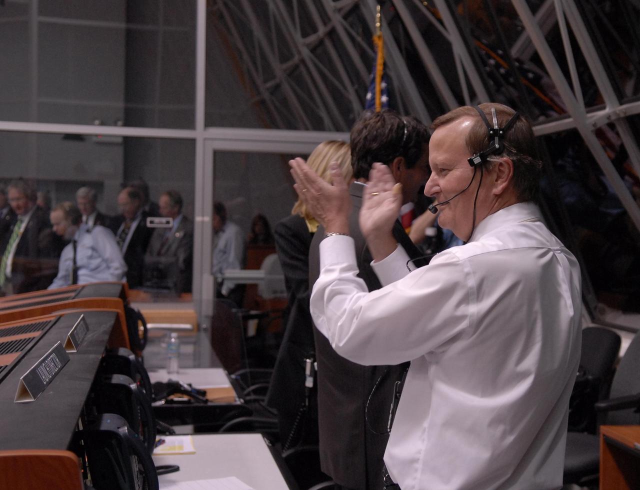 KENNEDY SPACE CENTER, FLA. --    In the firing room at the Launch Control Center, Shuttle Launch Director Mike Leinbach applauds the successful launch of Space Shuttle Discovery on mission STS-116.  Liftoff occurred on time at 8:47 p.m. EST.  This was the second launch attempt for mission STS-116.  The first launch attempt on Dec. 7 was postponed due a low cloud ceiling over Kennedy Space Center. This is Discovery's 33rd mission and the first night launch since 2002.   The 20th shuttle mission to the International Space Station, STS-116 carries another truss segment, P5. It will serve as a spacer, mated to the P4 truss that was attached in September.  After installing the P5, the crew will reconfigure and redistribute the power generated by two pairs of U.S. solar arrays. Landing is expected Dec. 21 at KSC.   Photo credit: NASA/Kim Shiflett