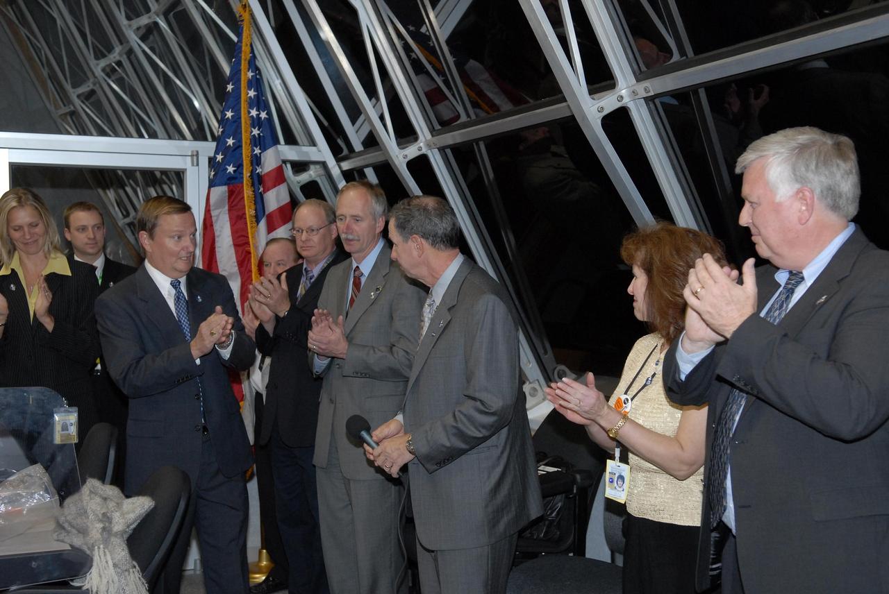 KENNEDY SPACE CENTER, FLA. --  In the firing room at the Launch Control Center, Shuttle Launch Director Mike Leinbach applauds with other NASA officials the successful second launch attempt of Space Shuttle Discovery on mission STS-116. Liftoff occurred on time at 8:47 p.m. EST.  Standing left to right are NASA Flow Director for Discovery Stephanie Stilson, Leinbach,  NASA KSC News Chief Bruce Buckingham, Associate Administrator for Space Operations Mission William Gerstenmaier,  NASA  Administrator Mike Griffin, Mrs. Griffin, and Kennedy Space Center Director Jim Kennedy. The first launch attempt on Dec. 7 was postponed due a low cloud ceiling over Kennedy Space Center. This is Discovery's 33rd mission and the first night launch since 2002.   The 20th shuttle mission to the International Space Station, STS-116 carries another truss segment, P5. It will serve as a spacer, mated to the P4 truss that was attached in September.  After installing the P5, the crew will reconfigure and redistribute the power generated by two pairs of U.S. solar arrays. Landing is expected Dec. 21 at KSC.   Photo credit: NASA/Kim Shiflett