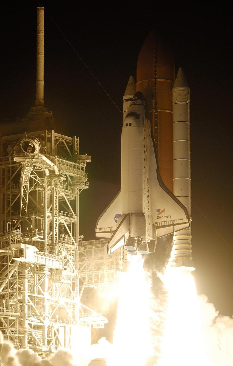 KENNEDY SPACE CENTER, FLA. --  Space Shuttle Discovery seems to be standing on the fiery columns erupting from the solid rocket boosters as it lifts off Launch Pad 39B on mission STS-116. The blazing light illuminated the launch pad and fixed service structure, at left.  Liftoff occurred on time at 8:47 p.m. EST. This was the second launch attempt for mission STS-116.  The first launch attempt on Dec. 7 was postponed due a low cloud ceiling over Kennedy Space Center. This is Discovery's 33rd mission and the first night launch since 2002.   The 20th shuttle mission to the International Space Station, STS-116 carries another truss segment, P5. It will serve as a spacer, mated to the P4 truss that was attached in September.  After installing the P5, the crew will reconfigure and redistribute the power generated by two pairs of U.S. solar arrays. Landing is expected Dec. 21 at KSC.   Photo courtesy of Nikon/Scott Andrews