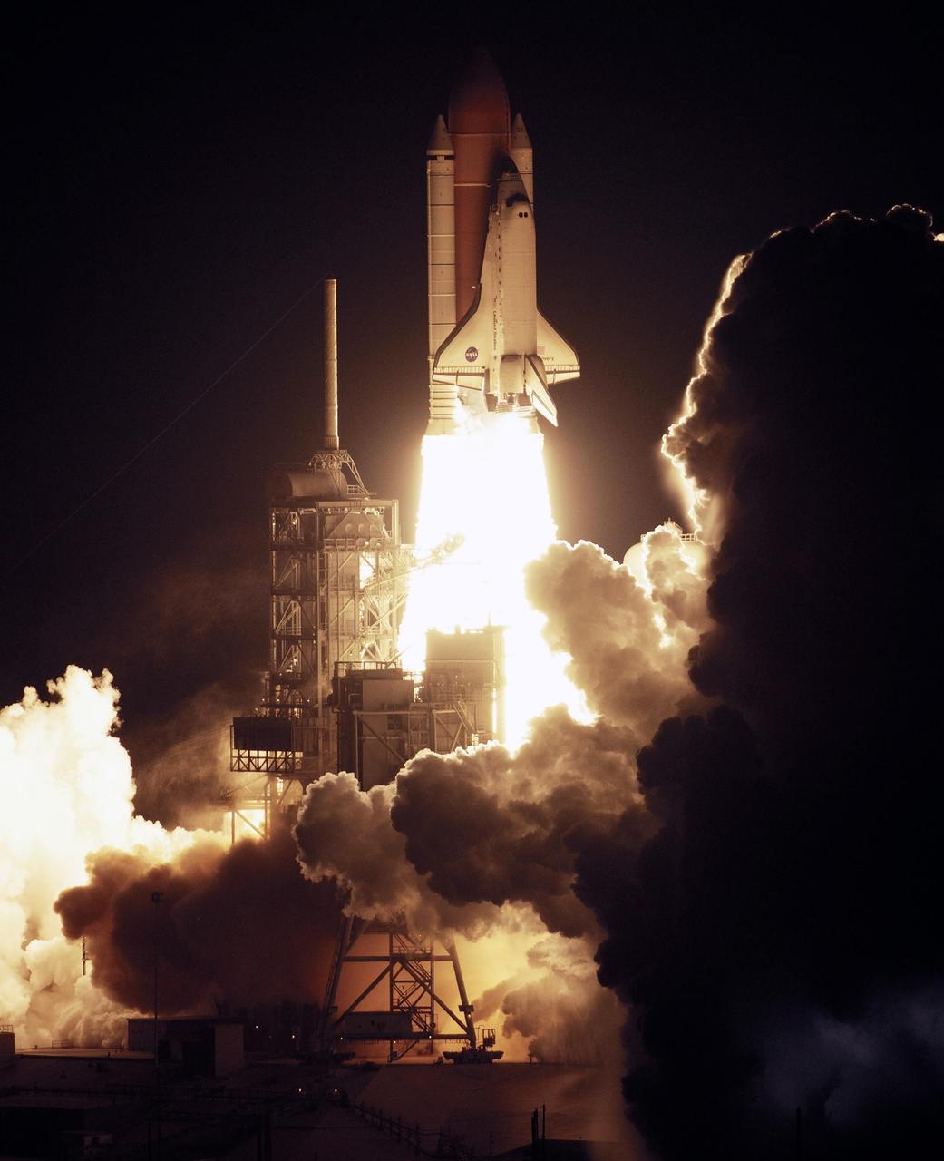 KENNEDY SPACE CENTER, FLA. --  Rising on columns of fire above the smoke and steam below, Space Shuttle Discovery leaps toward the sky past the lightning mast on Launch Pad 39B on mission STS-116.  Liftoff occurred on time at 8:47 p.m. EST. This was the second launch attempt for mission STS-116.  The first launch attempt on Dec. 7 was postponed due a low cloud ceiling over Kennedy Space Center. This is Discovery's 33rd mission and the first night launch since 2002.   The 20th shuttle mission to the International Space Station, STS-116 carries another truss segment, P5. It will serve as a spacer, mated to the P4 truss that was attached in September.  After installing the P5, the crew will reconfigure and redistribute the power generated by two pairs of U.S. solar arrays. Landing is expected Dec. 21 at KSC.   Photo courtesy of Nikon/Scott Andrews