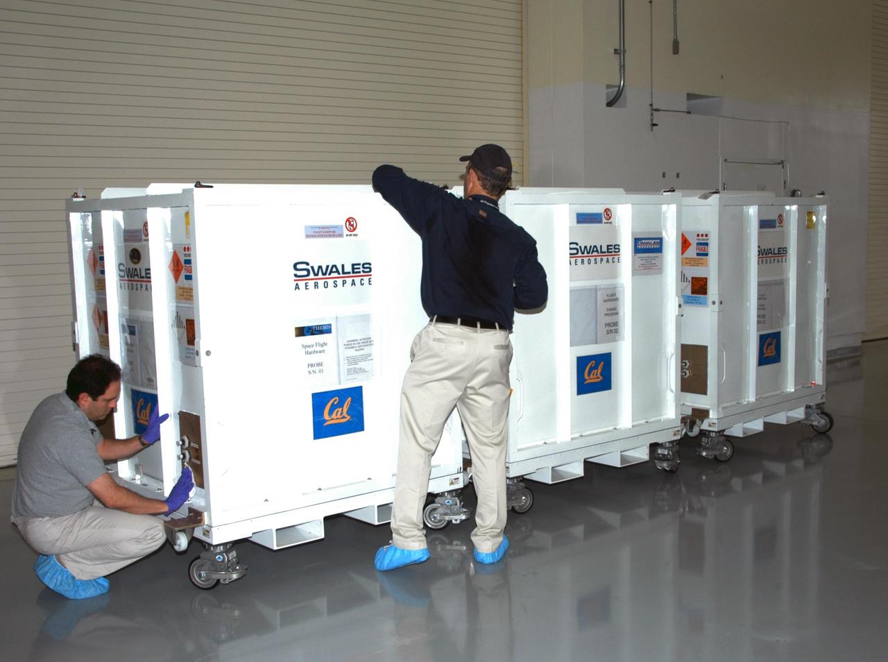 KENNEDY SPACE CENTER, FLA. --    Workers at Astrotech Space Operations in Titusville, Fla., wipe down the crates containing the probes of the THEMIS spacecraft.  THEMIS, which stands for Time History of Events and Macroscale Interactions during Substorms, comprises five identical probes that will study the dynamic and colorful eruptions of auroras. THEMIS is scheduled to  launch Feb. 15 from Cape Canaveral Air Force Station.  Photo credit: NASA/George Shelton