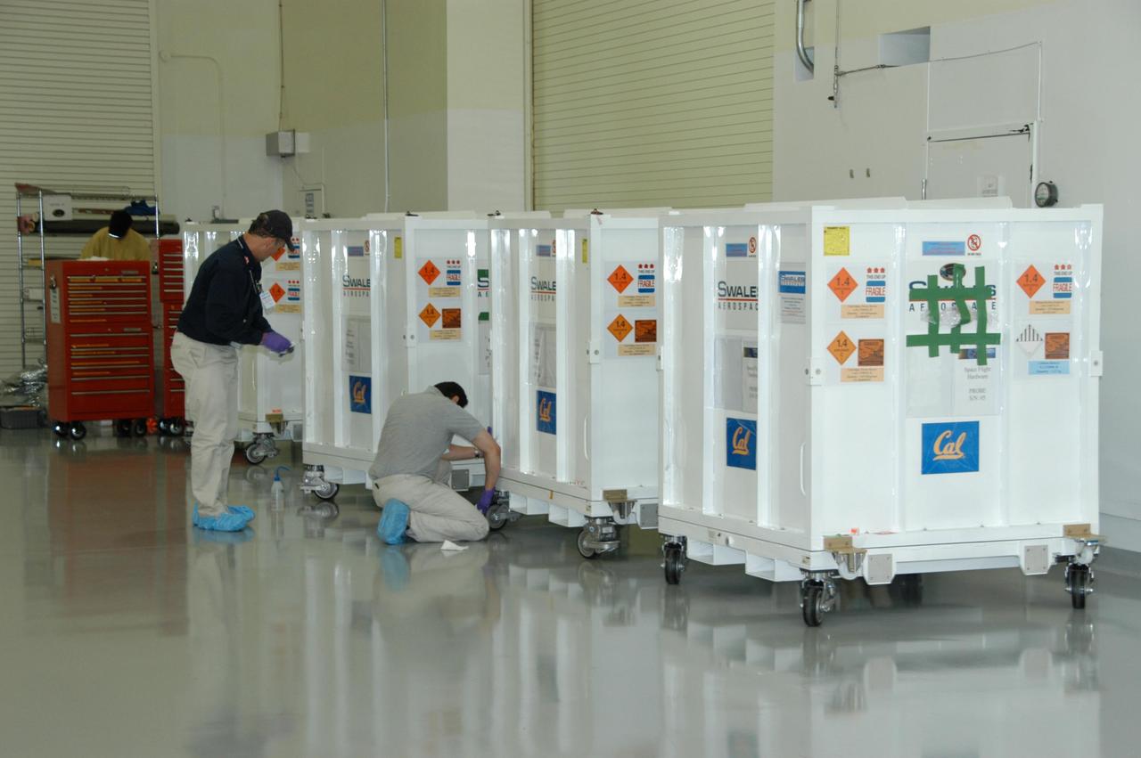 KENNEDY SPACE CENTER, FLA. --     Workers at Astrotech Space Operations in Titusville, Fla., wipe down the crates containing the probes of the THEMIS spacecraft. THEMIS, which stands for Time History of Events and Macroscale Interactions during Substorms, comprises five identical probes that will study the dynamic and colorful eruptions of auroras. THEMIS is scheduled to  launch Feb. 15 from Cape Canaveral Air Force Station.  Photo credit: NASA/George Shelton