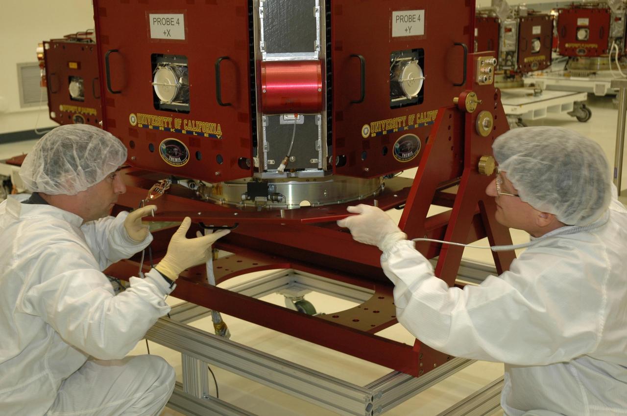 KENNEDY SPACE CENTER, FLA. --  At Astrotech Space Operations in Titusville, Fla., workers maneuver one of the THEMIS probes before installing bolt cutters that will separate each probe from the payload carrier. The probes will undergo weeks of testing and launch preparations. This includes a functional performance test to verify the state of health of each of the five probes and pressurization and leak checks of the reaction control systems.  THEMIS consists of five identical probes, the largest number of scientific satellites ever launched into orbit aboard a single rocket. This unique constellation of satellites will resolve the tantalizing mystery of what causes the spectacular sudden brightening of the aurora borealis and aurora australis - the fiery skies over the Earth's northern and southern polar regions. These lights are the visible manifestations of invisible energy releases, called geomagnetic substorms, in near-Earth space. THEMIS will not only seek to answer where and when substorms start, but will also provide clues as to how and why these space storms create havoc on satellites, terrestrial power grids, and communication systems.  THEMIS is scheduled to launch Feb. 15 from Cape Canaveral Air Force Station. Photo credit: NASA/Jack Pfaller