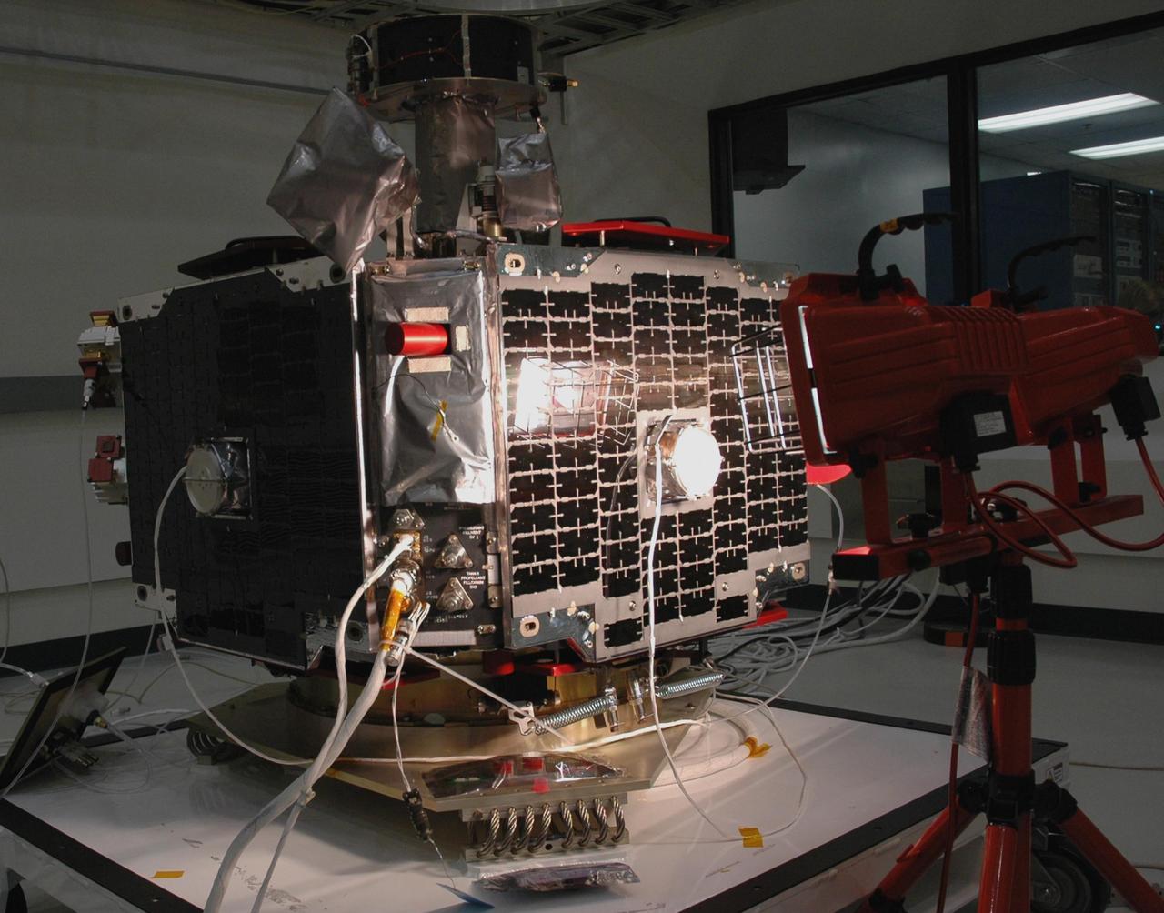 KENNEDY SPACE CENTER, FLA. -- At Astrotech Space Operations in Titusville, Fla., a solar array on one of the THEMIS probes undergoes a light test. THEMIS consists of five identical probes, the largest number of scientific satellites ever launched into orbit aboard a single rocket. This unique constellation of satellites will resolve the tantalizing mystery of what causes the spectacular sudden brightening of the aurora borealis and aurora australis - the fiery skies over the Earth's northern and southern polar regions. These lights are the visible manifestations of invisible energy releases, called geomagnetic substorms, in near-Earth space. THEMIS will not only seek to answer where and when substorms start, but will also provide clues as to how and why these space storms create havoc on satellites, terrestrial power grids, and communication systems. THEMIS is scheduled to launch Feb. 15 from Cape Canaveral Air Force Station. Photo credit: NASA/Jack Pfaller