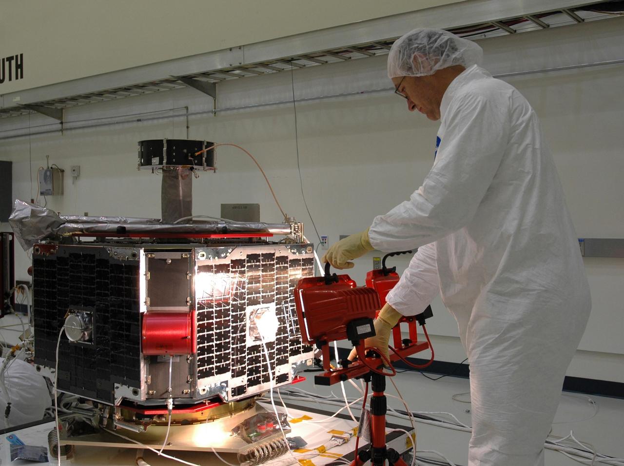 KENNEDY SPACE CENTER, FLA. -- At Astrotech Space Operations in Titusville, Fla., a technician arranges a light for a test on a solar array on one of the THEMIS probes. THEMIS consists of five identical probes, the largest number of scientific satellites ever launched into orbit aboard a single rocket. This unique constellation of satellites will resolve the tantalizing mystery of what causes the spectacular sudden brightening of the aurora borealis and aurora australis - the fiery skies over the Earth's northern and southern polar regions. These lights are the visible manifestations of invisible energy releases, called geomagnetic substorms, in near-Earth space. THEMIS will not only seek to answer where and when substorms start, but will also provide clues as to how and why these space storms create havoc on satellites, terrestrial power grids, and communication systems. THEMIS is scheduled to launch Feb. 15 from Cape Canaveral Air Force Station. Photo credit: NASA/Jack Pfaller