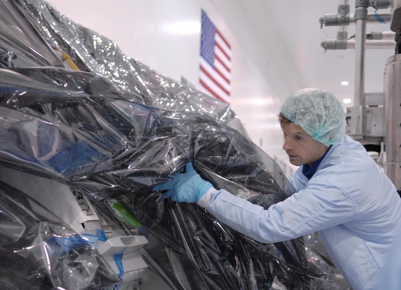 KENNEDY SPACE CENTER, FLA. -- In the Space Station Processing Facility, STS-117 Mission Specialist Steven Swanson looks under the protective wrapping at the S3/S4 starboard integrated truss segment that is part of the payload on the mission.   He and other crew members are at KSC to take part in a Crew Equipment Interface Test that allows them opportunities to become familiar with equipment and hardware for their mission. STS-117 will deliver the S3/S4 and another pair of solar arrays to the space station.  The 21st shuttle mission to the International Space Station, STS-117 is scheduled to launch no earlier than March 16.  Photo credit: NASA/Kim Shiflett