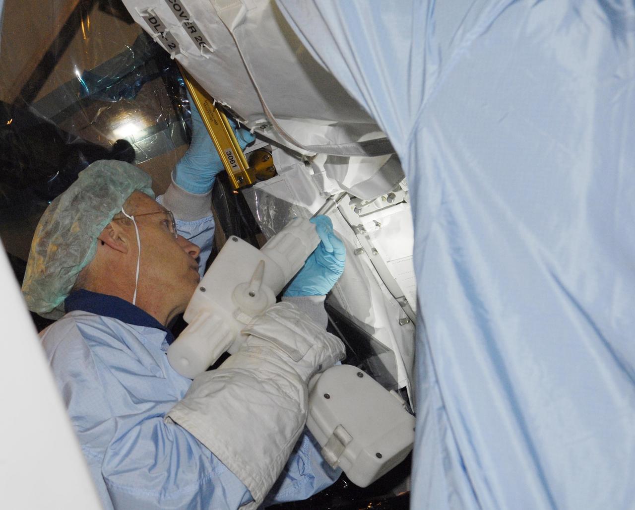 KENNEDY SPACE CENTER, FLA. --  In the Space Station Processing Facility, STS-117 Mission Specialist Patrick Forrester practices using a tool he will handle during the mission.  He and other crew members are at KSC to take part in a Crew Equipment Interface Test that allows them opportunities to become familiar with equipment and hardware for their mission. STS-117 will deliver the S3/S4 and another pair of solar arrays to the space station.  The 21st shuttle mission to the International Space Station, STS-117 is scheduled to launch no earlier than March 16.  Photo credit: NASA/Kim Shiflett