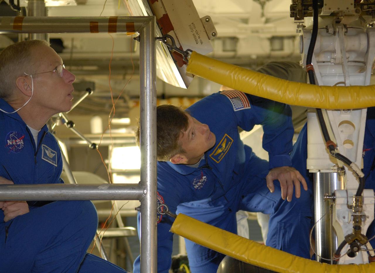 KENNEDY SPACE CENTER, FLA. --  In the Orbiter Processing Facility, STS-117 Mission Specialists Patrick Forrester (left) and Steven Swanson take a close look at the wheel well on orbiter Atlantis, their vehicle for the mission.  They and other crew members are at KSC to take part in a Crew Equipment Interface Test that allows them opportunities to become familiar with equipment and hardware for their mission. STS-117 will deliver the S3/S4 and another pair of solar arrays to the space station.  The 21st shuttle mission to the International Space Station, STS-117 is scheduled to launch no earlier than March 16.  Photo credit: NASA/Kim Shiflett