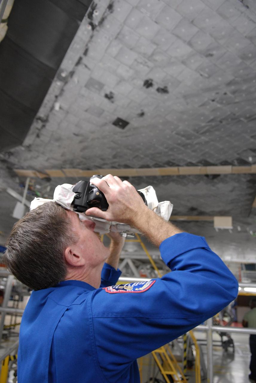 KENNEDY SPACE CENTER, FLA. --  In the Orbiter Processing Facility, STS-117 Mission Specialist James Reilly practices photographing the underside of the orbiter Atlantis with a camera he will use on the mission.  He and other crew members are at KSC to take part in a Crew Equipment Interface Test that allows them opportunities to become familiar with equipment and hardware for their mission. STS-117 will deliver the S3/S4 and another pair of solar arrays to the space station.  The 21st shuttle mission to the International Space Station, STS-117 is scheduled to launch no earlier than March 16.  Photo credit: NASA/Kim Shiflett