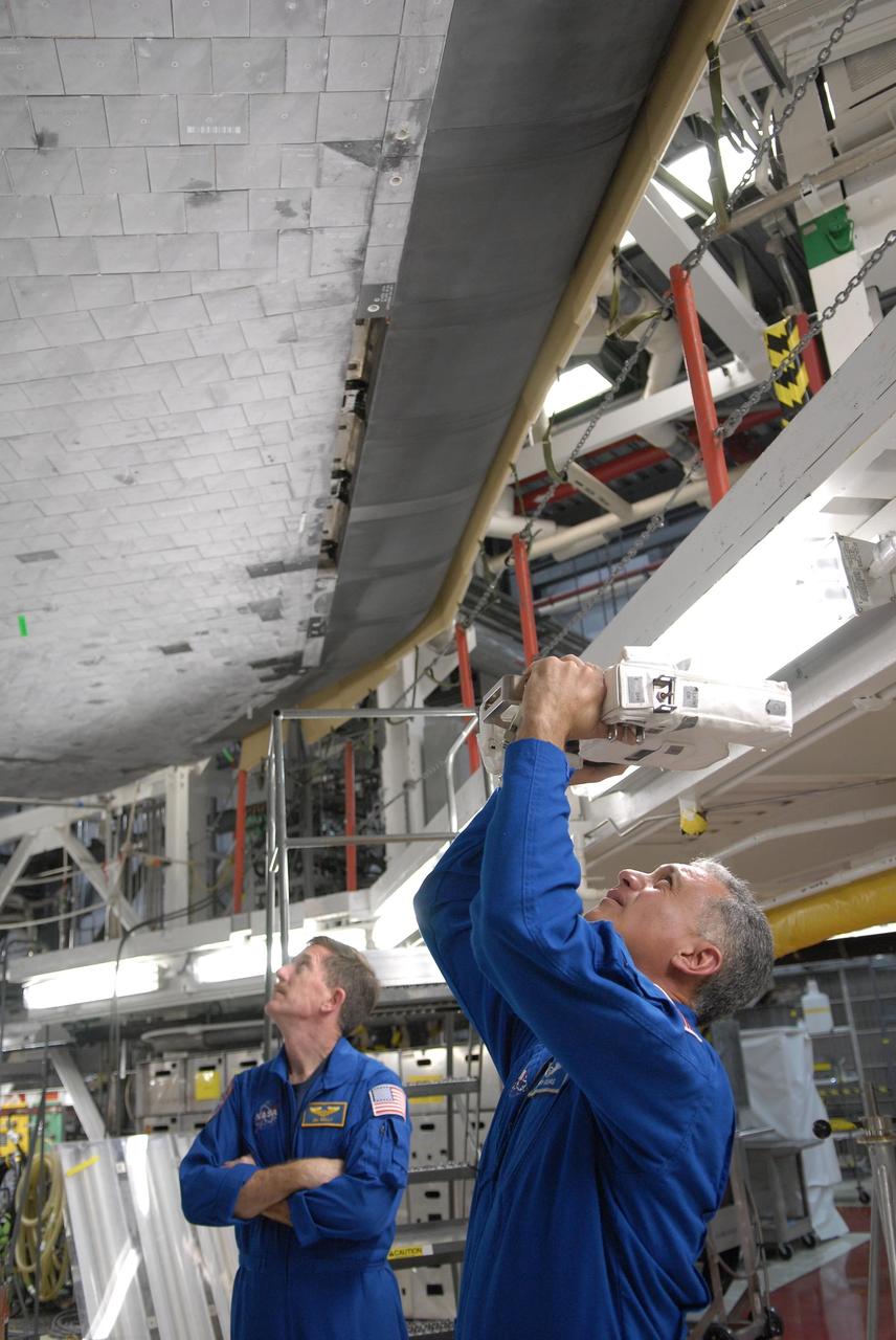 KENNEDY SPACE CENTER, FLA. --  In the Orbiter Processing Facility, STS-117 Mission Specialist John (Danny) Olivas  (right) again practices photographing the orbiter Atlantis with a camera he will use on the mission.  At left is Mission Specialist James Reilly.  They and other crew members are at KSC to take part in a Crew Equipment Interface Test that allows them opportunities to become familiar with equipment and hardware for their mission. STS-117 will deliver the S3/S4 and another pair of solar arrays to the space station.  The 21st shuttle mission to the International Space Station, STS-117 is scheduled to launch no earlier than March 16.  Photo credit: NASA/Kim Shiflett