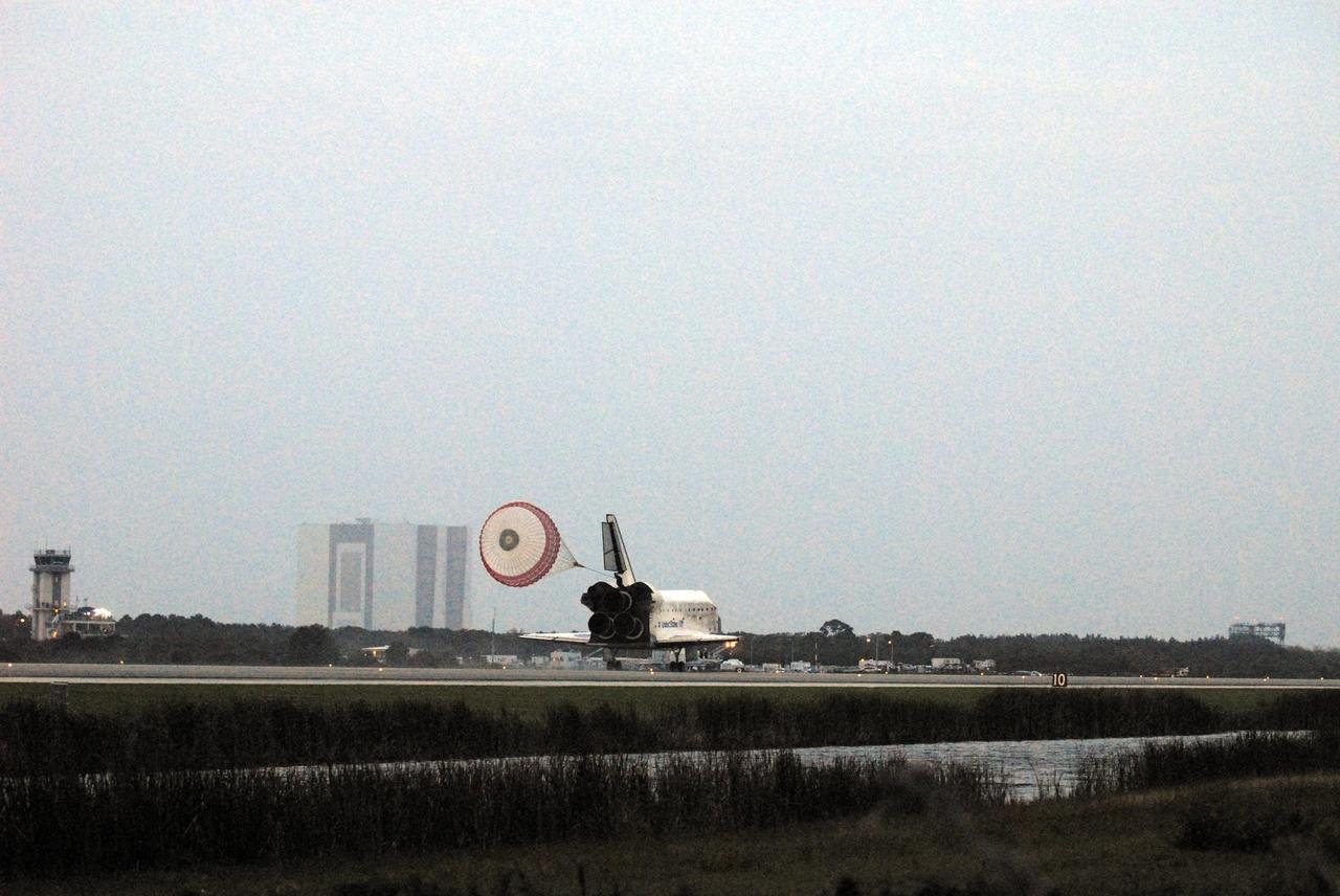 KENNEDY SPACE CENTER, FLA. -- Space Shuttle Discovery's drag chute unfurls upon landing on Runway 15 at NASA Kennedy Space Center's Shuttle Landing Facility as the sun sets on the shortest day of the year, concluding mission STS-116. In the background are the runway's Air Traffic Control Tower (far right) and the 525-foot-tall Vehicle Assembly Building. Aboard are Commander Mark Polansky, Pilot William Oefelein, and Mission Specialists Robert Curbeam, Joan Higginbotham, Nicholas Patrick and Christer Fuglesang, who represents the European Space Agency, as well as Thomas Reiter, who is returning from a 6-month stay on the International Space Station. During the mission, three spacewalks attached the P5 integrated truss structure to the station, and completed the rewiring of the orbiting laboratory's power system. A fourth spacewalk retracted a stubborn solar array. Main gear touchdown was at 5:32 p.m. EST. Nose gear touchdown was at 5:32:12 p.m. and wheel stop was at 5:32:52 p.m. At touchdown -- nominally about 2,500 ft. beyond the runway threshold -- the orbiter is traveling at a speed ranging from 213 to 226 mph. Discovery traveled 5,330,000 miles, landing on orbit 204. Mission elapsed time was 12 days, 20 hours, 44 minutes and 16 seconds. This is the 64th landing at KSC. Photo credit: NASA/Tom Joseph