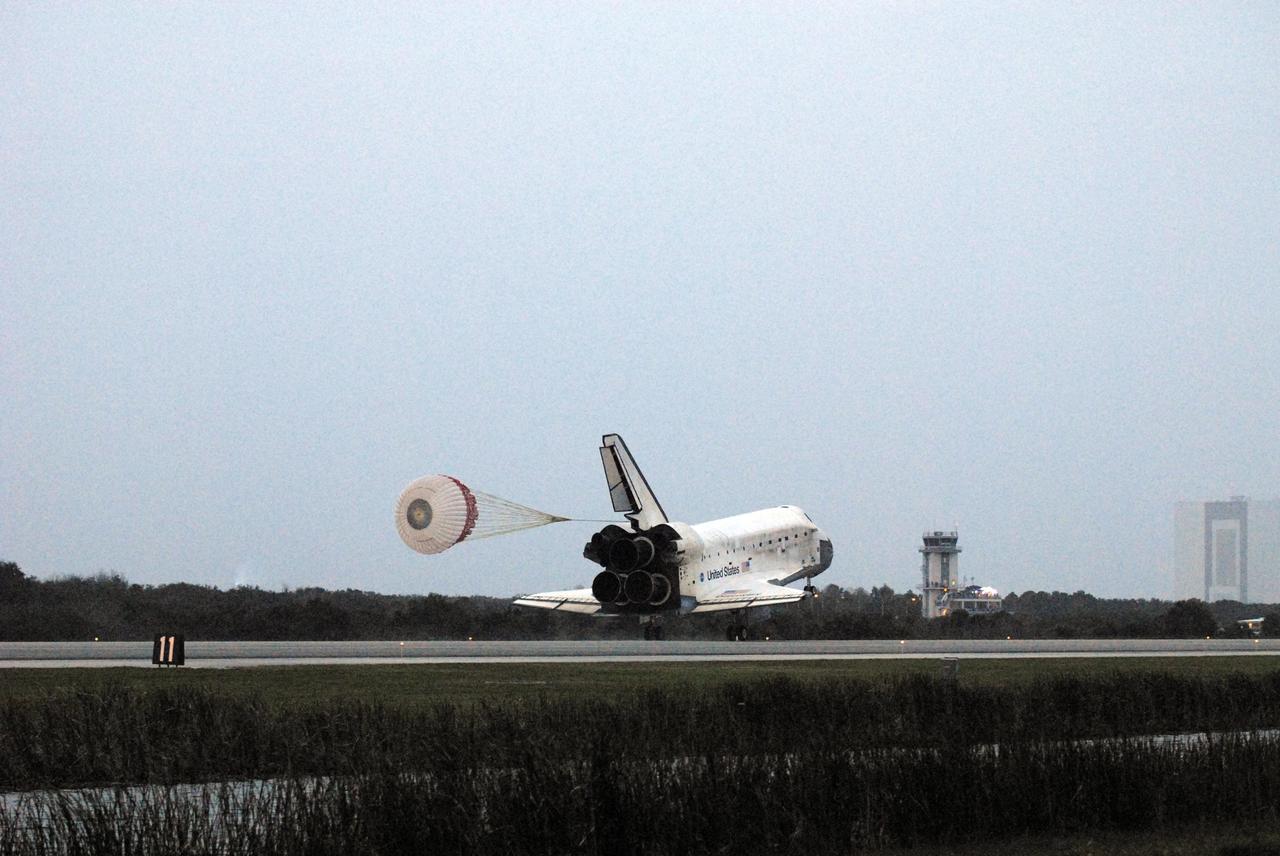 KENNEDY SPACE CENTER, FLA. -- Space Shuttle Discovery's drag chute unfurls upon landing on Runway 15 at NASA Kennedy Space Center's Shuttle Landing Facility as the sun sets on the shortest day of the year, concluding mission STS-116. In the background are the runway's Air Traffic Control Tower and the 525-foot-tall Vehicle Assembly Building (far right). Aboard are Commander Mark Polansky, Pilot William Oefelein, and Mission Specialists Robert Curbeam, Joan Higginbotham, Nicholas Patrick and Christer Fuglesang, who represents the European Space Agency, as well as Thomas Reiter, who is returning from a 6-month stay on the International Space Station. During the mission, three spacewalks attached the P5 integrated truss structure to the station, and completed the rewiring of the orbiting laboratory's power system. A fourth spacewalk retracted a stubborn solar array. Main gear touchdown was at 5:32 p.m. EST. Nose gear touchdown was at 5:32:12 p.m. and wheel stop was at 5:32:52 p.m. At touchdown -- nominally about 2,500 ft. beyond the runway threshold -- the orbiter is traveling at a speed ranging from 213 to 226 mph. Discovery traveled 5,330,000 miles, landing on orbit 204. Mission elapsed time was 12 days, 20 hours, 44 minutes and 16 seconds. This is the 64th landing at KSC. Photo credit: NASA/Tom Joseph