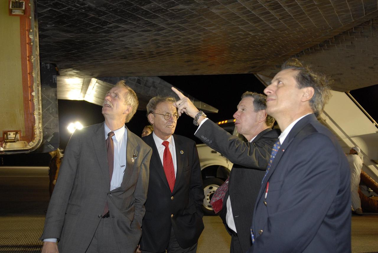 KENNEDY SPACE CENTER, FLA. --  Bill Gerstenmaier, NASA associate administrator for Space Operations; Sigmar Wittig, head of the DLR, the German Space Agency; Mike Griffin, NASA administrator; and Michel Tognini, head of the European Astronaut Center, examine the thermal protection system tiles beneath Space Shuttle Discovery following the landing of mission STS-116 on Runway 15 at NASA Kennedy Space Center's Shuttle Landing Facility. During the STS-116 mission, three spacewalks attached the P5 integrated truss structure to the station, and completed the rewiring of the orbiting laboratory's power system.  A fourth spacewalk retracted a stubborn solar array. Main gear touchdown was at 5:32 p.m. EST. Nose gear touchdown was at 5:32:12 p.m. and wheel stop was at 5:32:52 p.m.  At touchdown -- nominally about 2,500 ft. beyond the runway threshold -- the orbiter is traveling at a speed ranging from 213 to 226 mph. Discovery traveled 5,330,000 miles, landing on orbit 204. Mission elapsed time was 12 days, 20 hours, 44 minutes and 16 seconds. This is the 64th landing at KSC. Photo credit: NASA/Kim Shiflett