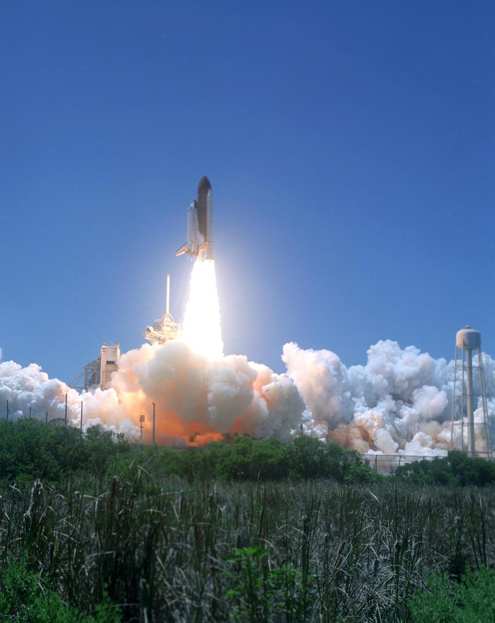 KENNEDY SPACE CENTER, FLA. -   Clearing the lighting rod on Launch Pad 39B, Space Shuttle Discovery makes history as the first to launch on Independence Day as it rockets into the clear blue sky.  Liftoff was on-time at 2:38 p.m. EDT.  During the 12-day mission, the STS-121 crew of seven will test new equipment and procedures to improve shuttle safety, as well as deliver supplies and make repairs to the International Space Station.  Landing is scheduled for July 16 or 17 at Kennedy's Shuttle Landing Facility.  Photo credit: NASA/Sandy Joseph & Robert Murray