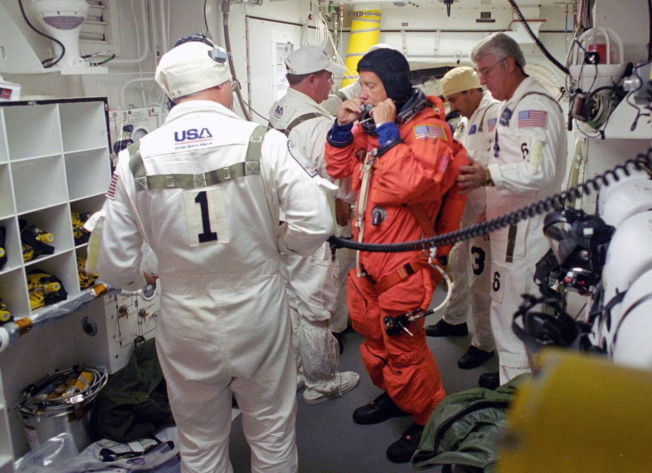 KENNEDY SPACE CENTER, FLA. -    In the White Room on Launch Pad 39B, STS-121 Commander Steven Lindsey is helped by the Closeout Crew to prepare his launch suit for entering Discovery and the launch. Situated on the end of the orbiter access arm, the White Room provides access into the orbiter on the pad.  The crew is preparing for the third launch attempt in four days; previous attempts were scrubbed due to weather concerns.  During the 12-day mission, the STS-121 crew will test new equipment and procedures to improve shuttle safety, as well as deliver supplies and make repairs to the International Space Station. The launch of Space Shuttle Discovery on mission STS-121 is the 115th shuttle flight and the 18th U.S. flight to the International Space Station.  Photo credit: NASA/Regina Mitchell-Ryall & Tony Gray