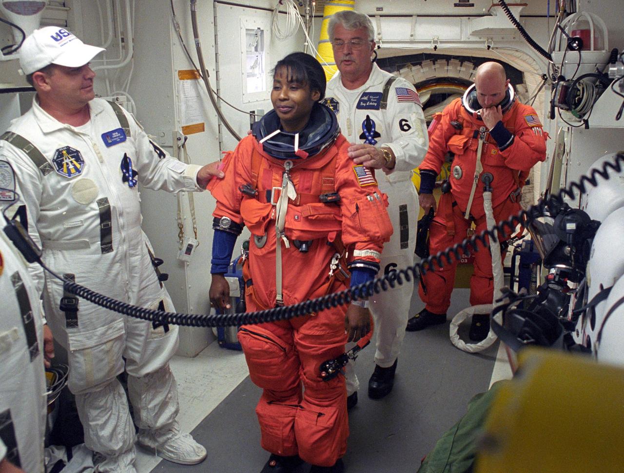 KENNEDY SPACE CENTER, FLA. -    In the White Room on Launch Pad 39B, STS-121 Mission Specialist Stephanie Wilson is helped by the Closeout Crew to secure her launch suit before entering Discovery.  Waiting in the back is Pilot Mark Kelly.  Situated on the end of the orbiter access arm, the White Room provides access into the orbiter on the pad.  The crew is preparing for the third launch attempt in four days; previous attempts were scrubbed due to weather concerns.  During the 12-day mission, the STS-121 crew will test new equipment and procedures to improve shuttle safety, as well as deliver supplies and make repairs to the International Space Station. The launch of Space Shuttle Discovery on mission STS-121 is the 115th shuttle flight and the 18th U.S. flight to the International Space Station.  Photo credit: NASA/Regina Mitchell-Ryall & Tony Gray