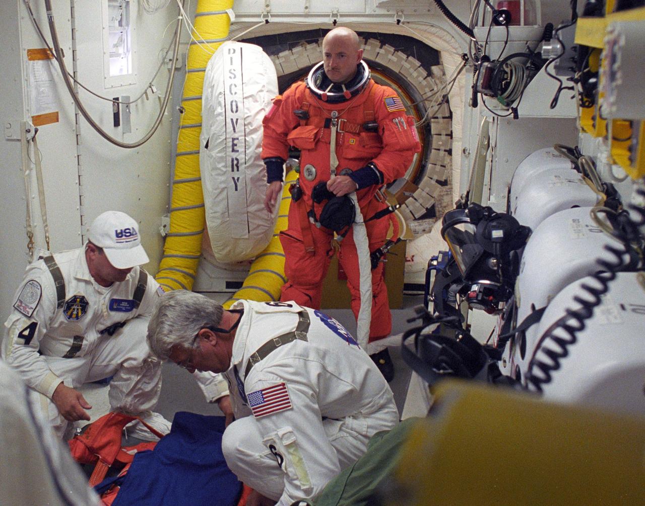 KENNEDY SPACE CENTER, FLA. -    In the White Room on Launch Pad 39B, STS-121 Pilot Mark Kelly heads for the Closeout Crew who will help with final preparations on his launch suit before entering Discovery.  Situated on the end of the orbiter access arm, the White Room provides access into the orbiter on the pad.  The crew is preparing for the third launch attempt in four days; previous attempts were scrubbed due to weather concerns.  During the 12-day mission, the STS-121 crew will test new equipment and procedures to improve shuttle safety, as well as deliver supplies and make repairs to the International Space Station. The launch of Space Shuttle Discovery on mission STS-121 is the 115th shuttle flight and the 18th U.S. flight to the International Space Station.