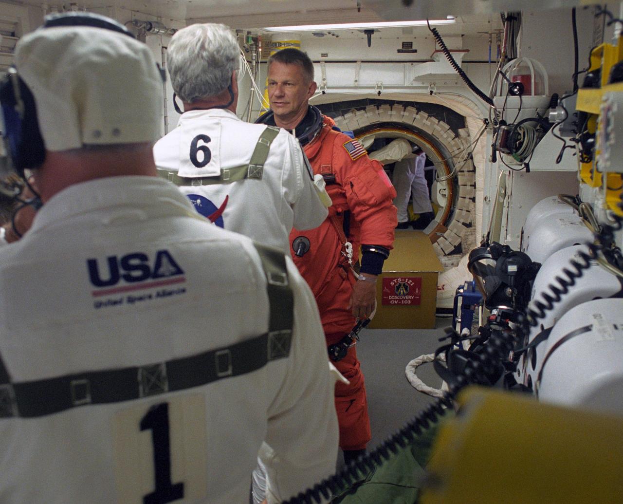 KENNEDY SPACE CENTER, FLA. -    In the White Room on Launch Pad 39B, STS-121 Mission Specialist Piers Sellers gets help from the Closeout Crew with final preparations on his launch suit before entering Discovery.  Situated on the end of the orbiter access arm, the White Room provides access into the orbiter on the pad.  The crew is preparing for the third launch attempt in four days; previous attempts were scrubbed due to weather concerns.  During the 12-day mission, the STS-121 crew will test new equipment and procedures to improve shuttle safety, as well as deliver supplies and make repairs to the International Space Station. The launch of Space Shuttle Discovery on mission STS-121 is the 115th shuttle flight and the 18th U.S. flight to the International Space Station.