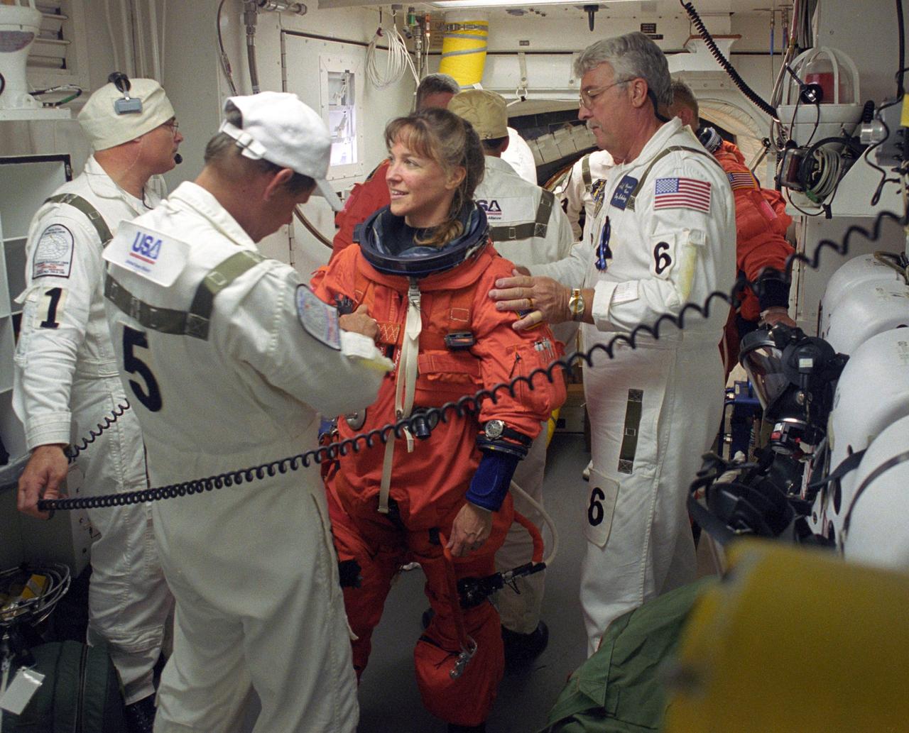 KENNEDY SPACE CENTER, FLA. -    In In the White Room on Launch Pad 39B, STS-121 Mission Specialist Lisa Nowak is helped by the Closeout Crew with final preparations on her launch suit before entering Discovery.  Situated on the end of the orbiter access arm, the White Room provides access into the orbiter on the pad.  The crew is preparing for the third launch attempt in four days; previous attempts were scrubbed due to weather concerns.  During the 12-day mission, the STS-121 crew will test new equipment and procedures to improve shuttle safety, as well as deliver supplies and make repairs to the International Space Station. The launch of Space Shuttle Discovery on mission STS-121 is the 115th shuttle flight and the 18th U.S. flight to the International Space Station.