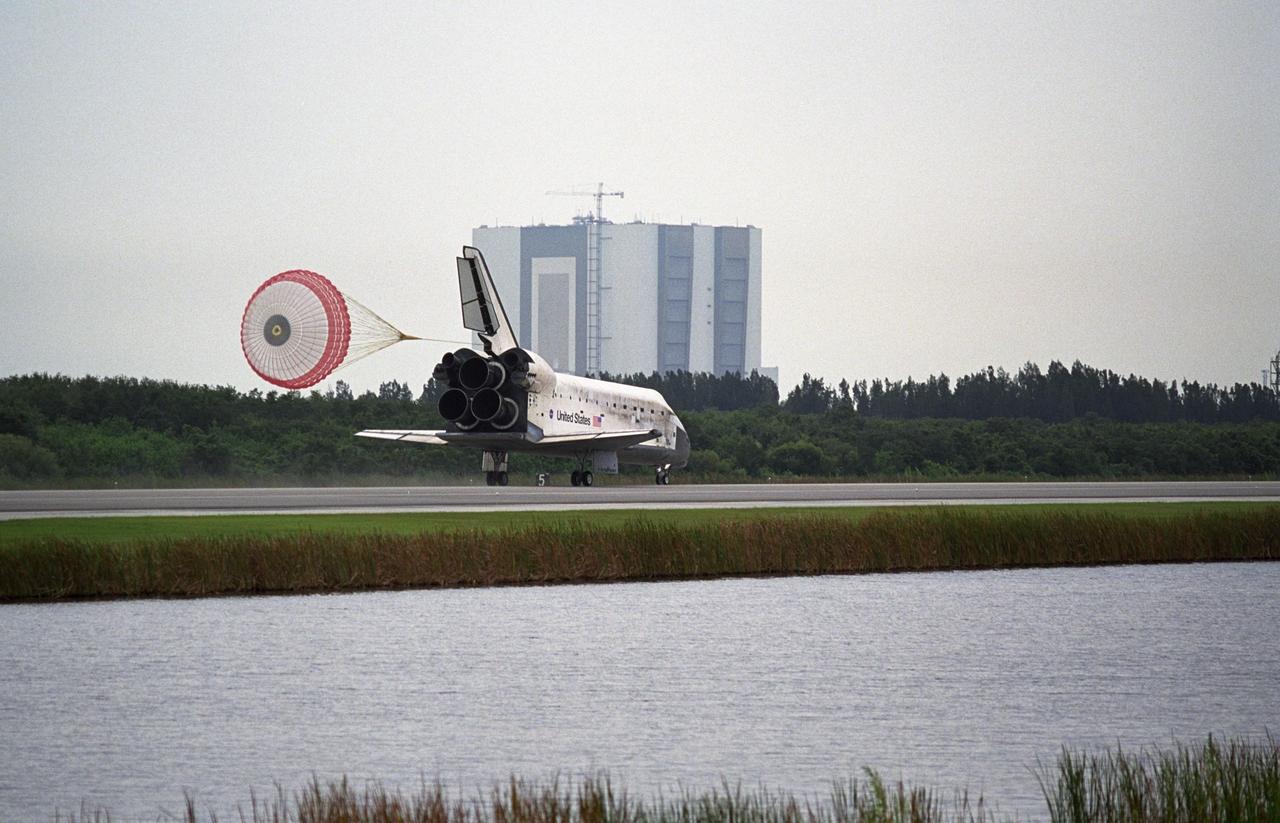 KENNEDY SPACE CENTER, FLA. -    With the help of a drag chute to slow its speed, the orbiter Discovery lands on Runway 15 at NASA's Shuttle Landing Facility after completing mission STS-121 to the International Space Station.  In the background is the Vehicle Assembly Building.  Discovery traveled  5.3 million miles, landing on orbit 202.  Mission elapsed time was 12 days, 18 hours, 37 minutes and 54 seconds.  Main gear touchdown occurred on time at 9:14:43 EDT.  Wheel stop was at 9:15:49 EDT.  The returning crew members aboard are Commander Steven Lindsey, Pilot Mark Kelly and Mission Specialists Piers Sellers, Michael Fossum, Lisa Nowak and Stephanie Wilson.  Mission Specialist Thomas Reiter, who launched with the crew on July 4, remained on the station to join the Expedition 13 crew there.  The landing is the 62nd at Kennedy Space Center and the 32nd for Discovery.  During the mission, the STS-121 crew tested new equipment and procedures to improve shuttle safety, and delivered supplies and made repairs to the International Space Station. Photo credit: NASA/Regina Mitchell-Ryall