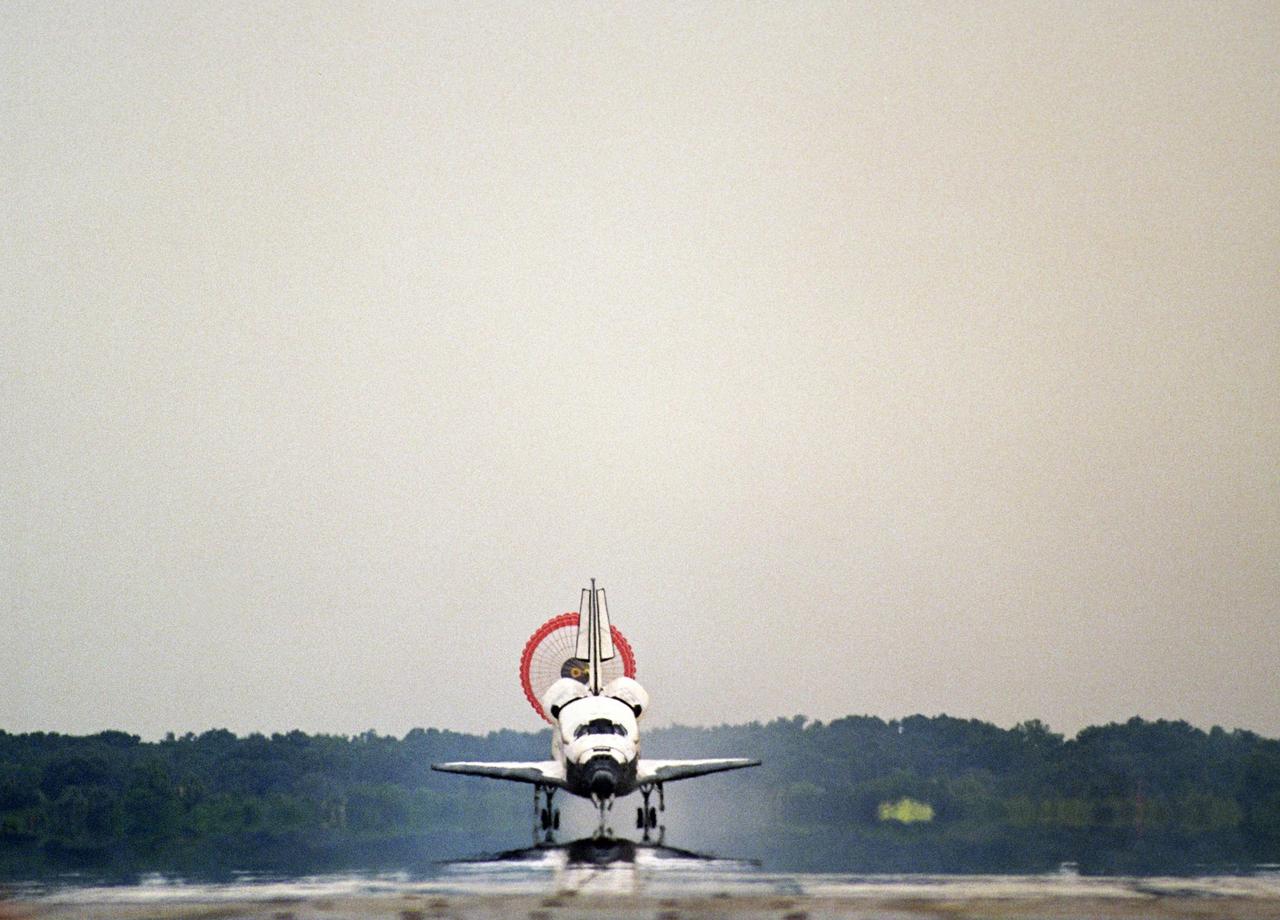 KENNEDY SPACE CENTER, FLA. - With its drag chute flowing behind it, the orbiter Discovery touches down on Runway 15 at NASA's Shuttle Landing Facility, completing mission STS-121 to the International Space Station. At touchdown -- nominally about 2,500 ft. beyond the runway threshold -- the orbiter is traveling at a speed ranging from 213 to 226 mph. Discovery traveled 5.3 million miles, landing on orbit 202. Mission elapsed time was 12 days, 18 hours, 37 minutes and 54 seconds. Main gear touchdown occurred on time at 9:14:43 EDT. Wheel stop was at 9:15:49 EDT. The returning crew members aboard are Commander Steven Lindsey, Pilot Mark Kelly and Mission Specialists Piers Sellers, Michael Fossum, Lisa Nowak and Stephanie Wilson. Mission Specialist Thomas Reiter, who launched with the crew on July 4, remained on the station to join the Expedition 13 crew there. The landing is the 62nd at Kennedy Space Center and the 32nd for Discovery. During the mission, the STS-121 crew tested new equipment and procedures to improve shuttle safety, and delivered supplies and made repairs to the International Space Station. Photo credit: NASA/Tony Gray & Tim Powers