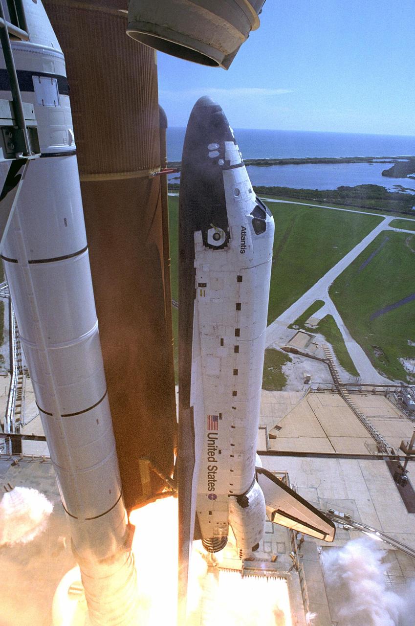 KENNEDY SPACE CENTER, FLA. -  Flaming rockets propel Space Shuttle Atlantis off Launch Pad 39B  for a rendezvous with the International Space Station on mission STS-115. In the background is the Atlantic Ocean.  Appearing above the nose of the orbiter is the end of the gaseous vent line that leads from the hood, or beanie cap, which has been moved away from the shuttle for liftoff. Liftoff was on-time at 11:14:55 a.m. EDT. After several launch attempts were scrubbed due to weather and technical concerns, this launch was executed perfectly. Mission STS-115 is the 116th space shuttle flight, the 27th flight for orbiter Atlantis, and the 19th U.S. flight to the International Space Station.  During the mission, Atlantis' astronauts will deliver and install the 17.5-ton, bus-sized P3/P4 integrated truss segment on the station. The girder-like truss includes a set of giant solar arrays, batteries and associated electronics and will provide one-fourth of the total power-generation capability for the completed station. STS-115 is scheduled to last 11 days with a planned landing at KSC