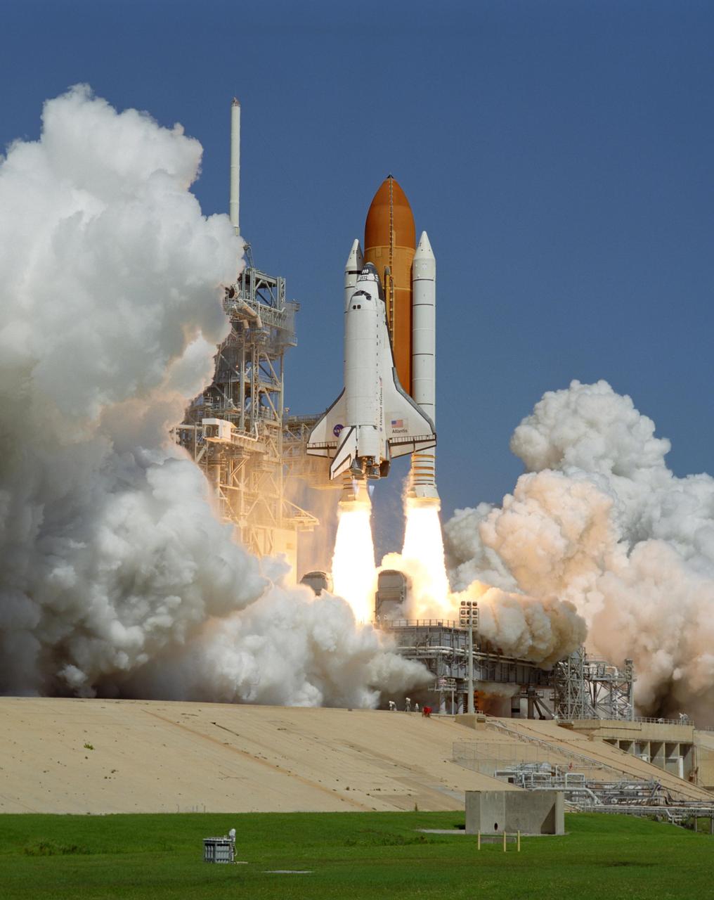 KENNEDY SPACE CENTER, FLA. -    Twin columns of fire from the solid rocket boosters hurl Space Shuttle Atlantis off Launch Pad 39B into the sky for a rendezvous with the International Space Station on mission STS-115. Clouds of smoke and steam spread across the pad and the fixed service structure at left, topped by the lightning mast.   Atlantis is heading for a rendezvous with the International Space Station on mission STS-115.  Liftoff was on-time at 11:14:55 a.m. EDT. After several launch attempts were scrubbed due to weather and technical concerns, this launch was executed perfectly. Mission STS-115 is the 116th space shuttle flight, the 27th flight for orbiter Atlantis, and the 19th U.S. flight to the International Space Station.  During the mission, Atlantis' astronauts will deliver and install the 17.5-ton, bus-sized P3/P4 integrated truss segment on the station. The girder-like truss includes a set of giant solar arrays, batteries and associated electronics and will provide one-fourth of the total power-generation capability for the completed station. STS-115 is scheduled to last 11 days with a planned landing at KSC