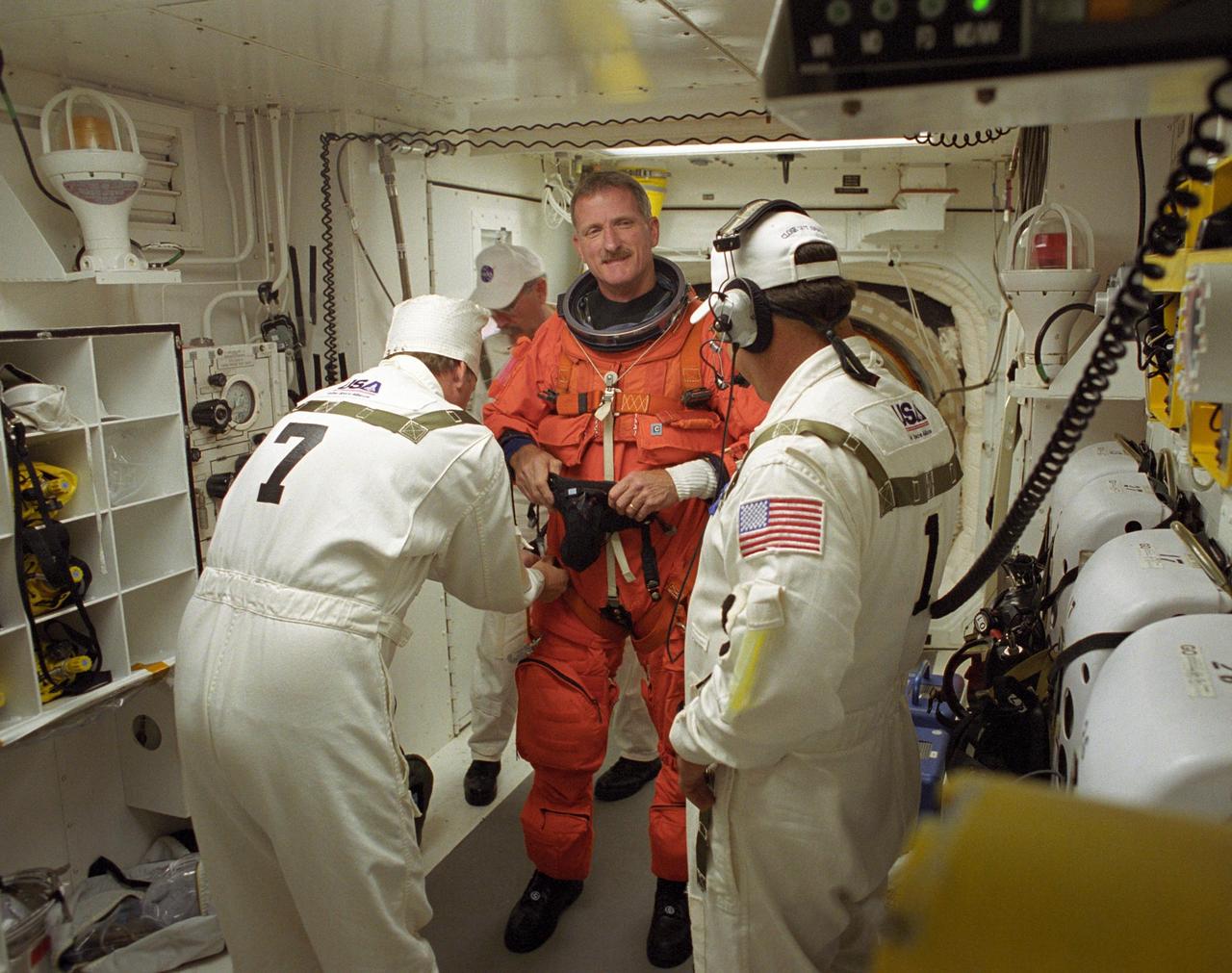 KENNEDY SPACE CENTER, FLA. -    In the White Room on Launch Pad 39B, STS-115 Mission Specialist Joseph Tanner gets help with his launch suit from the closeout crew before entering Space Shuttle Atlantis. Tanner is making his fourth shuttle flight. During the mission, Atlantis' astronauts will deliver and install the 17.5-ton, bus-sized P3/P4 integrated truss segment on the station. The girder-like truss includes a set of giant solar arrays, batteries and associated electronics and will provide one-fourth of the total power-generation capability for the completed station. This mission is the 116th space shuttle flight, the 27th flight for orbiter Atlantis, and the 19th U.S. flight to the International Space Station.  STS-115 is scheduled to last 11 days with a planned landing at KSC.