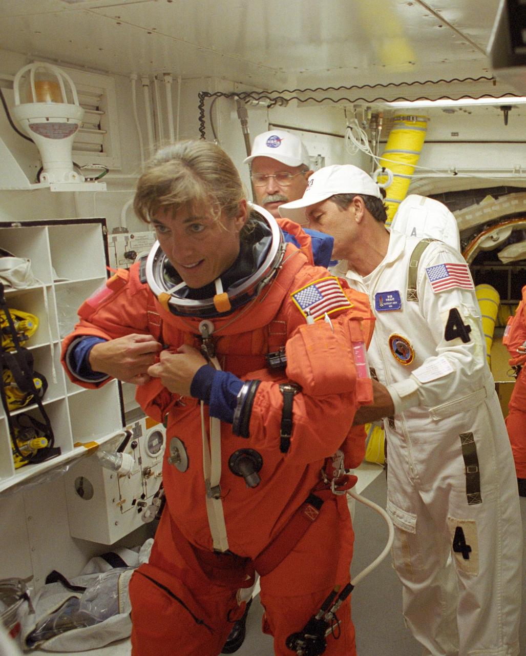 KENNEDY SPACE CENTER, FLA. -    In the White Room on Launch Pad 39B, STS-115 Mission Specialist Heidemarie Stefanyshyn-Piper gets help with her launch suit from the closeout crew before entering Space Shuttle Atlantis.  Piper is making her first shuttle flight.  During the mission, Atlantis' astronauts will deliver and install the 17.5-ton, bus-sized P3/P4 integrated truss segment on the station. The girder-like truss includes a set of giant solar arrays, batteries and associated electronics and will provide one-fourth of the total power-generation capability for the completed station. This mission is the 116th space shuttle flight, the 27th flight for orbiter Atlantis, and the 19th U.S. flight to the International Space Station.  STS-115 is scheduled to last 11 days with a planned landing at KSC
