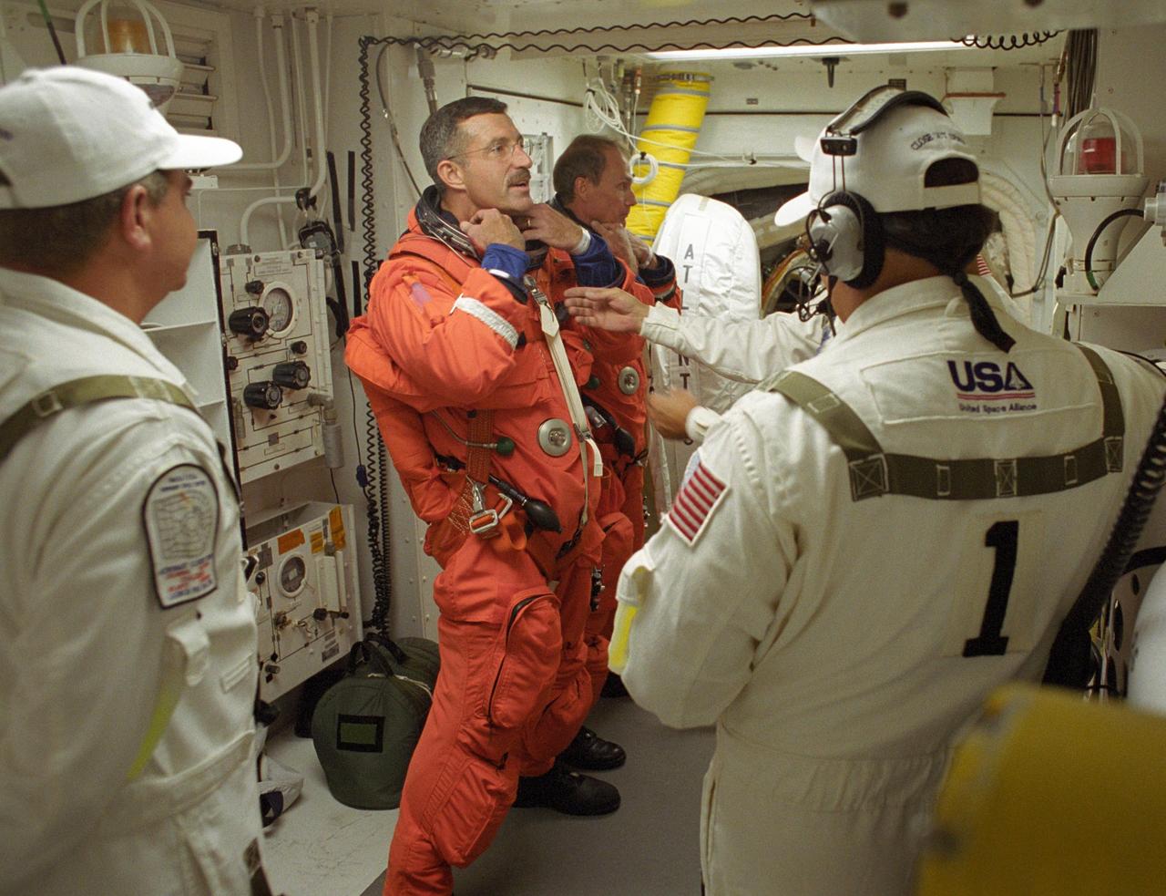 KENNEDY SPACE CENTER, FLA. -  STS-115 Mission Specialists Daniel Burbank (left) and Steven MacLean get help with their launch suits from the closeout crew before entering Space Shuttle Atlantis.   Both astronauts are making their second shuttle flights.  MacLean is with the Canadian Space Agency.  During the mission, Atlantis' astronauts will deliver and install the 17.5-ton, bus-sized P3/P4 integrated truss segment on the station. The girder-like truss includes a set of giant solar arrays, batteries and associated electronics and will provide one-fourth of the total power-generation capability for the completed station. This mission is the 116th space shuttle flight, the 27th flight for orbiter Atlantis, and the 19th U.S. flight to the International Space Station.  STS-115 is scheduled to last 11 days with a planned landing at KSC