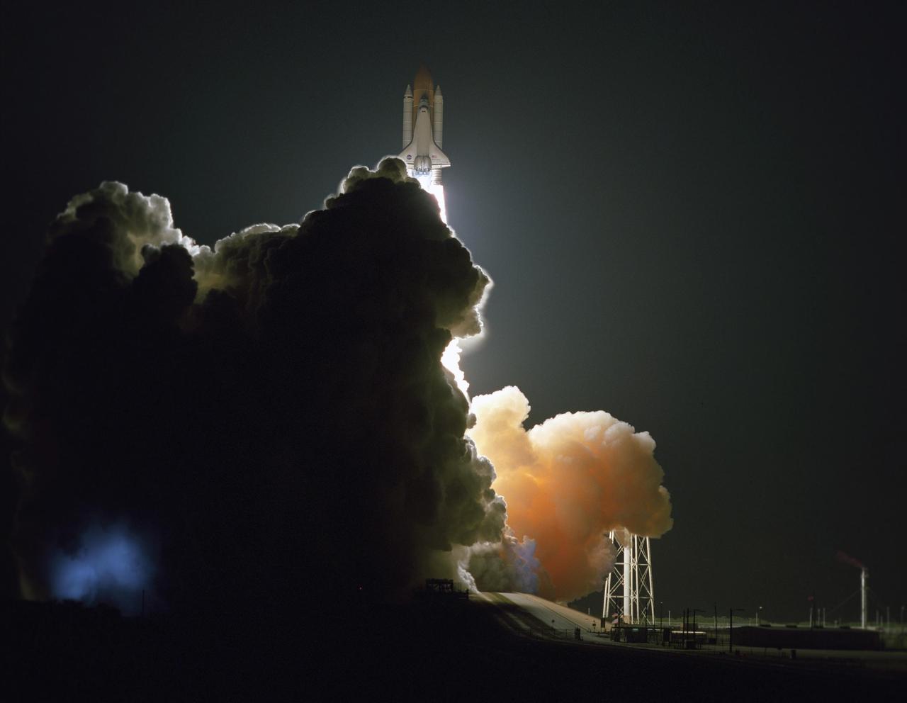 KENNEDY SPACE CENTER, FLA. --  Emerging from behind the clouds of smoke and steam generated by its liftoff, Space Shuttle Discovery leaps toward the sky past the lightning mast on Launch Pad 39B on mission STS-116.  Liftoff occurred on time at 8:47 p.m. EST. This was the second launch attempt of Discovery on mission STS-116.  The first launch attempt on Dec. 7 was postponed due a low cloud ceiling over Kennedy Space Center. This is Discovery's 33rd mission and the first night launch since 2002.   The 20th shuttle mission to the International Space Station, STS-116 carries another truss segment, P5. It will serve as a spacer, mated to the P4 truss that was attached in September.  After installing the P5, the crew will reconfigure and redistribute the power generated by two pairs of U.S. solar arrays. Landing is expected Dec. 21 at KSC.   Photo credit: NASA/Sandra Joseph, Robert Murray, Chris Lynch