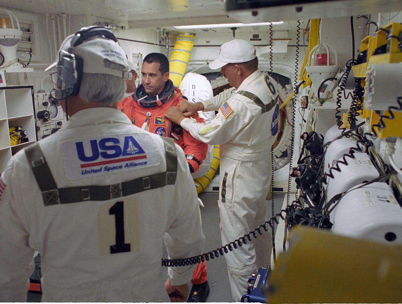 KENNEDY SPACE CENTER, FLA. --   STS-116 Commander William Oefelein is helped by the closeout crew in the White Room to secure his launch suit before climbing into Space Shuttle Discovery. The White Room is at the end of the orbiter access arm that extends from the fixed service structure and provides entry into the orbiter.  The first launch attempt of STS-116 on Dec. 7 was postponed due a low cloud ceiling over Kennedy Space Center. This second launch attempt is scheduled for 8:47 p.m. This is Discovery's 33rd mission and the first night launch since 2002.   The 20th shuttle mission to the International Space Station, STS-116 carries another truss segment, P5. It will serve as a spacer, mated to the P4 truss that was attached in September.  After installing the P5, the crew will reconfigure and redistribute the power generated by two pairs of U.S. solar arrays. Landing is expected Dec. 21 at KSC.    Photo credit: NASA/Tony Gray & Don Kight