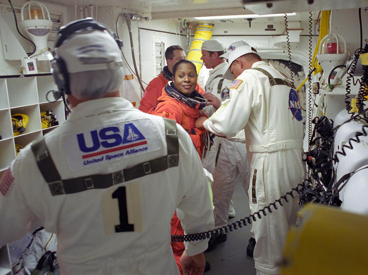 KENNEDY SPACE CENTER, FLA. --  STS-116 Mission Specialist Joan Higginbotham is helped by the closeout crew in the White Room to secure her launch suit before climbing into Space Shuttle Discovery.  Behind her is Mission Specialist Nicholas Patrick. The White Room is at the end of the orbiter access arm that extends from the fixed service structure and provides entry into the orbiter.  The first launch attempt of STS-116 on Dec. 7 was postponed due a low cloud ceiling over Kennedy Space Center. This second launch attempt is scheduled for 8:47 p.m. This is Discovery's 33rd mission and the first night launch since 2002.   The 20th shuttle mission to the International Space Station, STS-116 carries another truss segment, P5. It will serve as a spacer, mated to the P4 truss that was attached in September.  After installing the P5, the crew will reconfigure and redistribute the power generated by two pairs of U.S. solar arrays. Landing is expected Dec. 21 at KSC.    Photo credit: NASA/Tony Gray & Don Kight