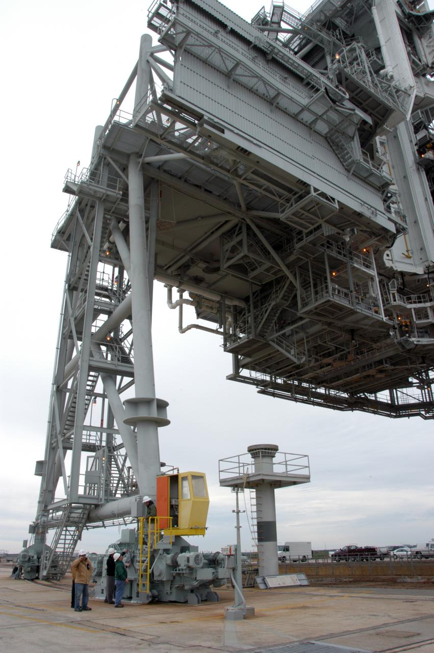 Workers on Launch Pad 39A get ready to begin the movement of the rotating service structure above them. The RSS has not been rotated for more than a year during the maintenance and upgrades on the pad. Some of the work included sandblasting the structure to remove rust and repainting. In addition, the RSS was jacked up and a new upper-bearing race assembly installed where the RSS pivots against the fixed service structure and a half-inch steel plate added. Pad 39A is being made ready for its first launch in four years, the upcoming STS-117 on March 15. 