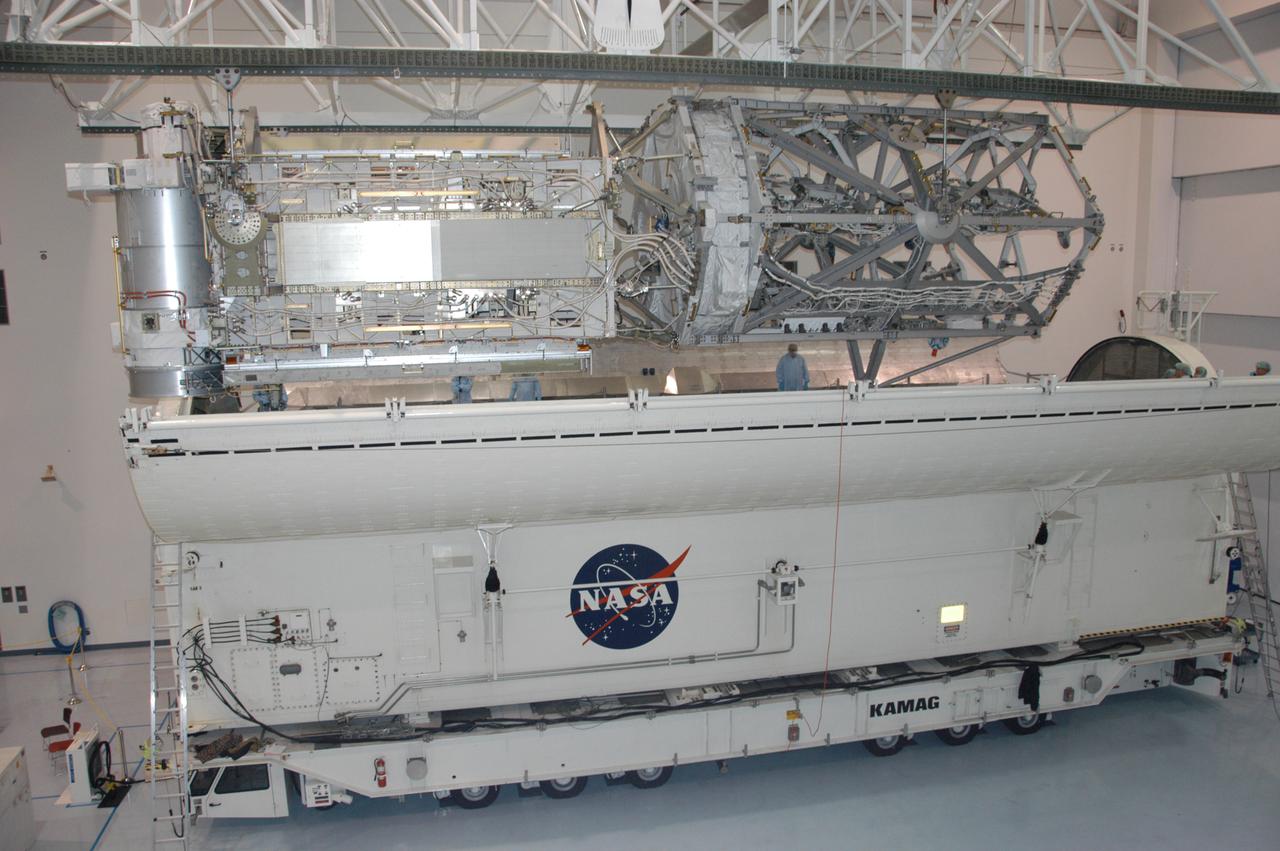 In the Space Station Processing Facility, an overhead crane lowers the S3/S4 integrated truss toward the open doors of the payload canister. After it is stowed in the canister, the S3/S4 truss will be transported to the launch pad. The truss is the payload on mission STS-117, targeted for launch on March 15.