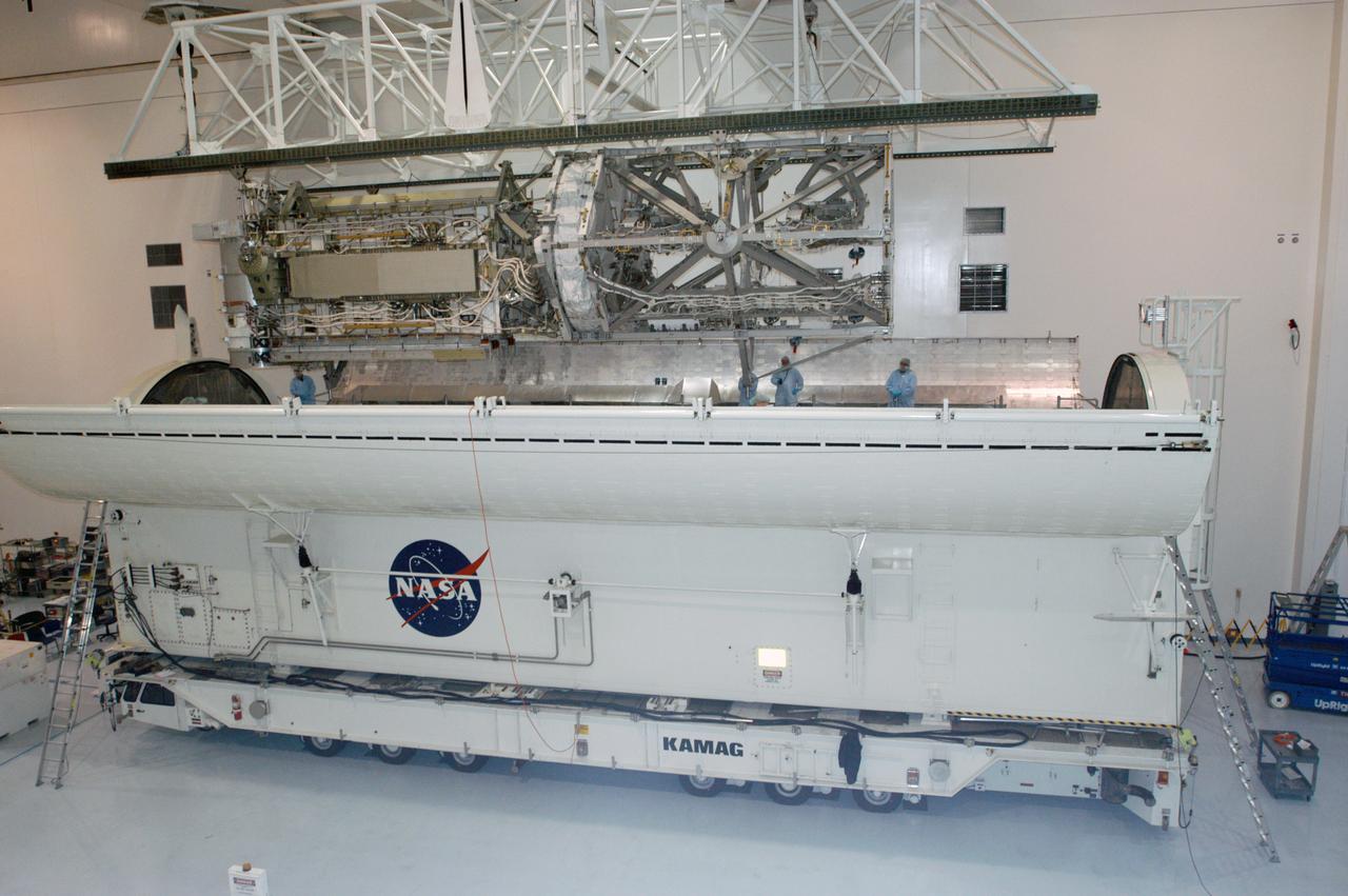 In the Space Station Processing Facility, an overhead crane lowers the S3/S4 integrated truss into the open bay of the payload canister. After it is stowed in the canister, the S3/S4 truss will be transported to the launch pad. The truss is the payload on mission STS-117, targeted for launch on March 15.