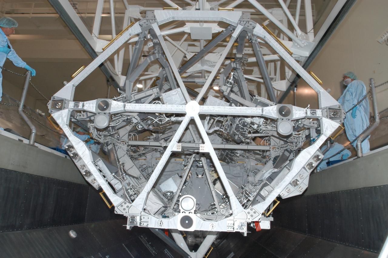 In the Space Station Processing Facility, an overhead crane settles the S3/S4 integrated truss into the payload canister. After it is stowed in the canister, the S3/S4 truss will be transported to the launch pad. The truss is the payload on mission STS-117, targeted for launch on March 15. 