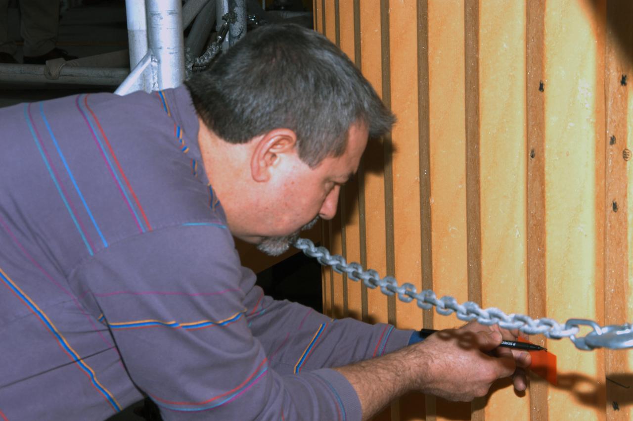 In high bay 1 of the Vehicle Assembly Building, a technician marks off an area for inspection on Atlantis' external tank. A severe thunderstorm with golf ball-sized hail caused visible divots in the giant tank's foam insulation and minor surface damage to about 26 heat shield tiles on the shuttle's left wing. Further evaluation of the tank is necessary to get an accurate accounting of foam damage and determine the type of repair required and the time needed for that work. A new target launch date has not been determined, but teams will focus on preparing Atlantis for liftoff in late April on mission STS-117. 