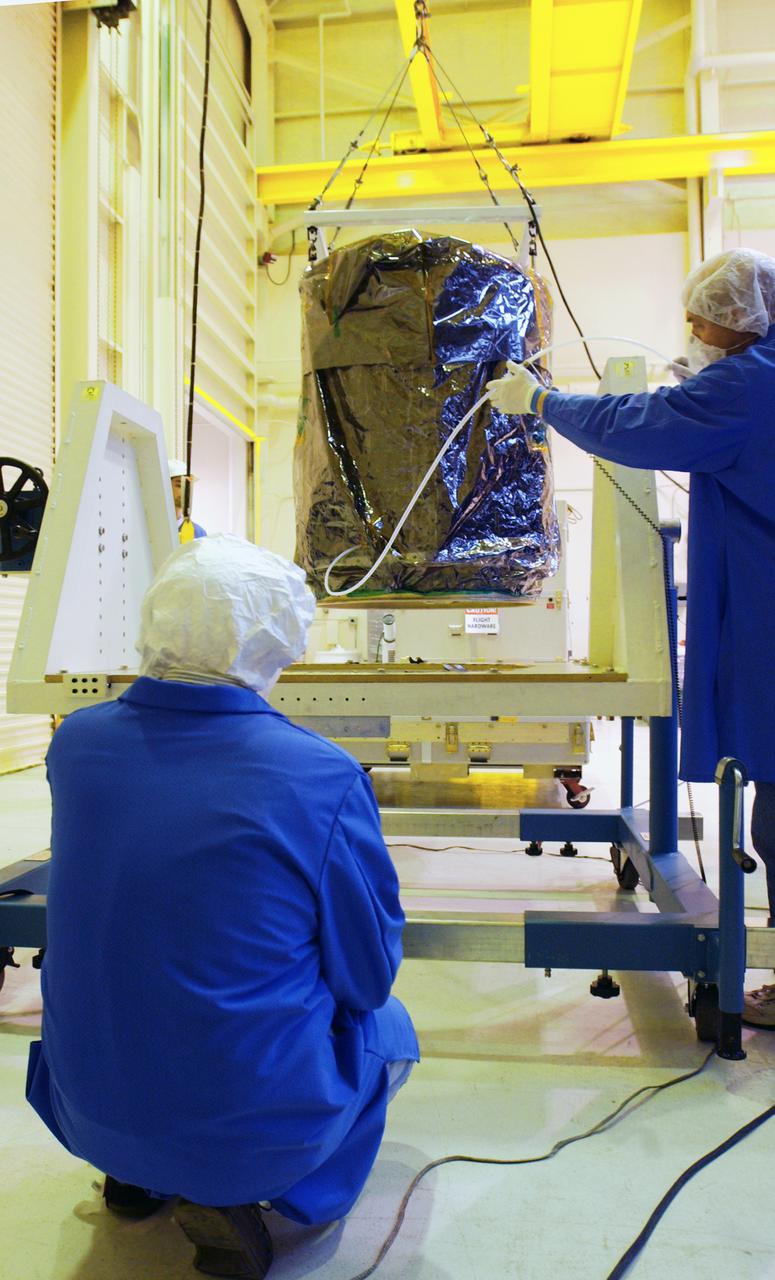 Inside a clean room at Vandenberg Air Force Base in California, workers observe NASA's Aeronomy of Ice in the Mesosphere, or AIM, spacecraft as it is lowered onto a scale. AIM is the seventh Small Explorers mission under NASA's Explorer Program. The program provides frequent flight opportunities for world-class scientific investigations from space within heliophysics and astrophysics. The AIM spacecraft will fly three instruments designed to study polar mesospheric clouds located at the edge of space, 50 miles above the Earth's surface in the coldest part of the planet's atmosphere. The mission's primary goal is to explain why these clouds form and what has caused them to become brighter and more numerous and appear at lower latitudes in recent years. AIM's results will provide the basis for the study of long-term variability in the mesospheric climate and its relationship to global climate change. AIM is scheduled to be mated to the Pegasus XL during the second week of April, after which final inspections will be conducted. Launch is scheduled for April 25.