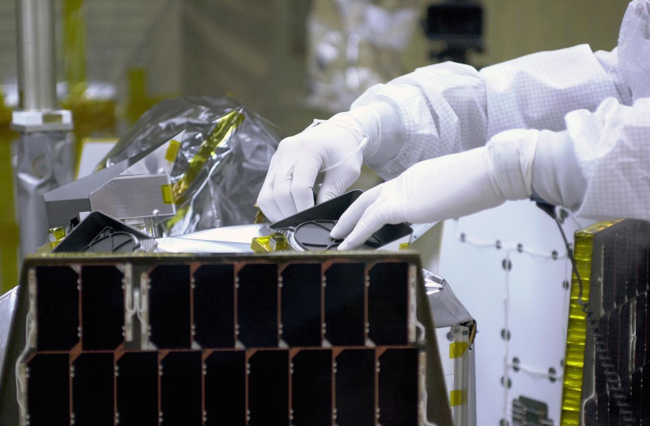 In a clean-room environment at North Vandenberg Air Force Base, technicians remove covers from instruments in the AIM spacecraft while solar panels are partially deployed. AIM will fly three instruments designed to study polar mesospheric clouds located at the edge of space, 50 miles above the Earth's surface in the coldest part of the planet's atmosphere. The mission's primary goal is to explain why these clouds form and what has caused them to become brighter and more numerous and appear at lower latitudes in recent years. AIM's results will provide the basis for the study of long-term variability in the mesospheric climate and its relationship to global climate change. AIM is scheduled to be mated to the Pegasus XL during the second week of April, after which final inspections will be conducted. Launch is scheduled for April 25.