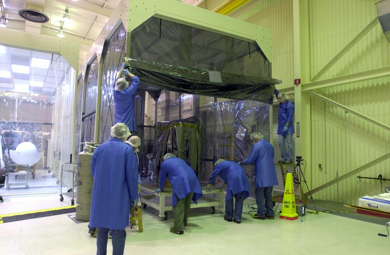 In Building 1555 on North Vandenberg Air Force Base in California, technicians work on the separation system to be mated to the AIM spacecraft, hovering above it. AIM, which stands for Aeronomy of Ice in the Mesosphere, is being prepared for integrated testing and a flight simulation. The AIM spacecraft will fly three instruments designed to study polar mesospheric clouds located at the edge of space, 50 miles above the Earth's surface in the coldest part of the planet's atmosphere. The mission's primary goal is to explain why these clouds form and what has caused them to become brighter and more numerous and appear at lower latitudes in recent years. AIM's results will provide the basis for the study of long-term variability in the mesospheric climate and its relationship to global climate change. AIM is scheduled to be mated to its launch vehicle, Orbital Sciences' Pegasus XL, during the second week of April, after which final inspections will be conducted. Launch is scheduled for April 25.