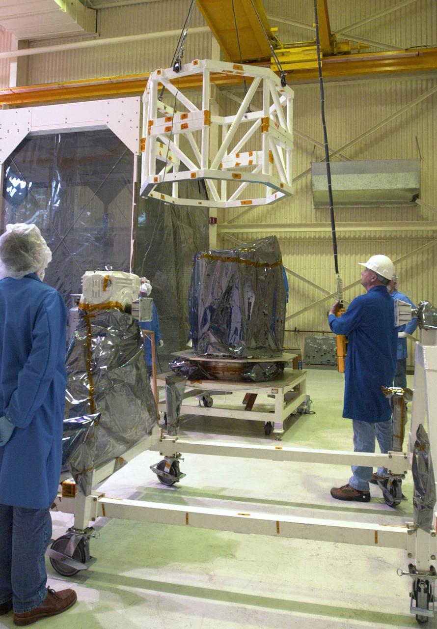 In Building 1555 on North Vandenberg Air Force Base in California, technicians maneuver the spacecraft handling fixture toward the AIM spacecraft. AIM, which stands for Aeronomy of Ice in the Mesosphere, is being prepared for integrated testing and a flight simulation. The AIM spacecraft will fly three instruments designed to study polar mesospheric clouds located at the edge of space, 50 miles above the Earth's surface in the coldest part of the planet's atmosphere. The mission's primary goal is to explain why these clouds form and what has caused them to become brighter and more numerous and appear at lower latitudes in recent years. AIM's results will provide the basis for the study of long-term variability in the mesospheric climate and its relationship to global climate change. AIM is scheduled to be mated to its launch vehicle, Orbital Sciences' Pegasus XL, during the second week of April, after which final inspections will be conducted. Launch is scheduled for April 25.