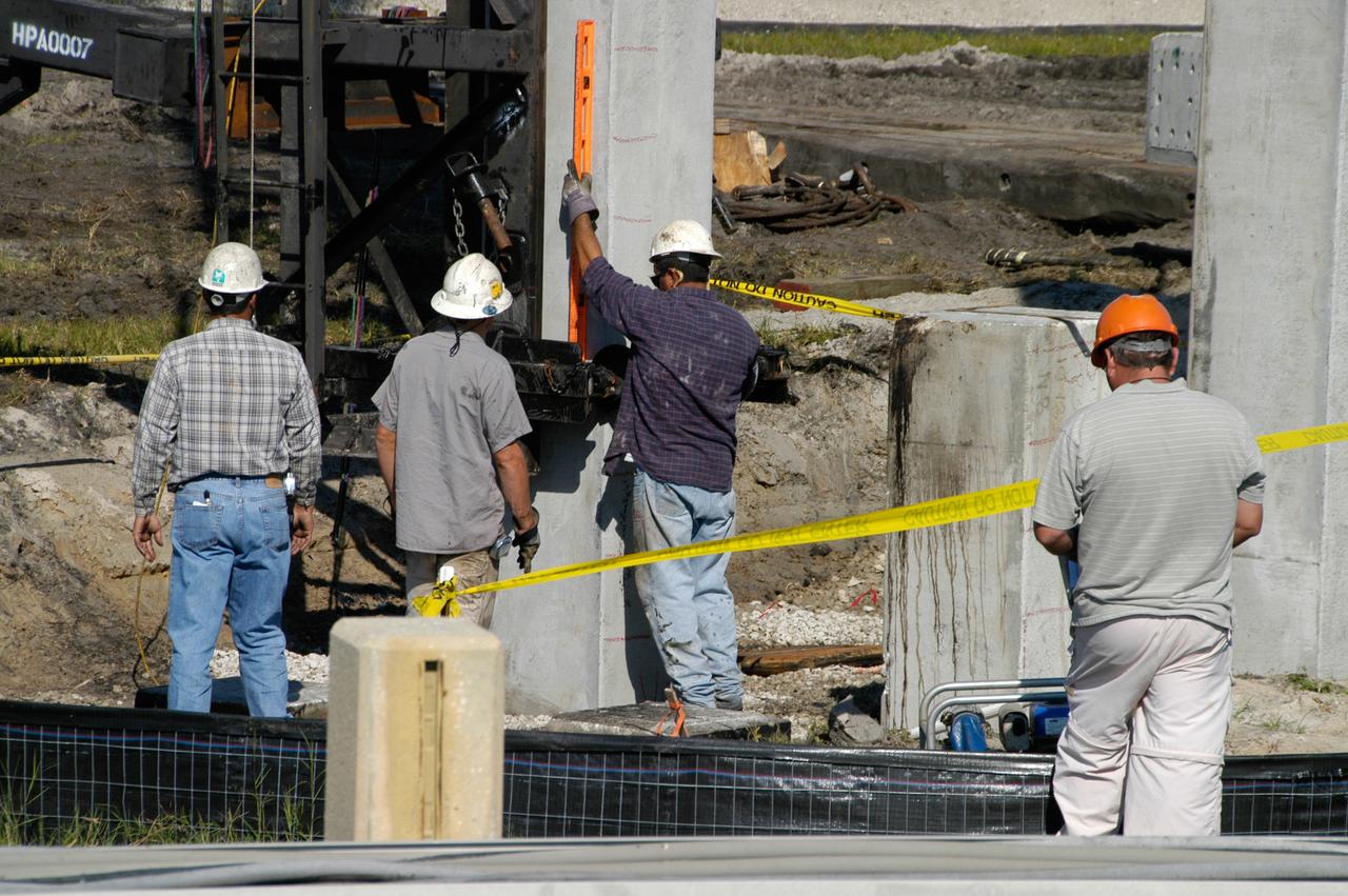 On Launch Pad 39B at NASA's Kennedy Space Center, workers measure the piling being pounded into the ground to help construct lightning towers for the Constellation Program and Ares/Orion launches. Pad B will be the site of the first Ares vehicle launch, including Ares I-X which is scheduled for April 2009.